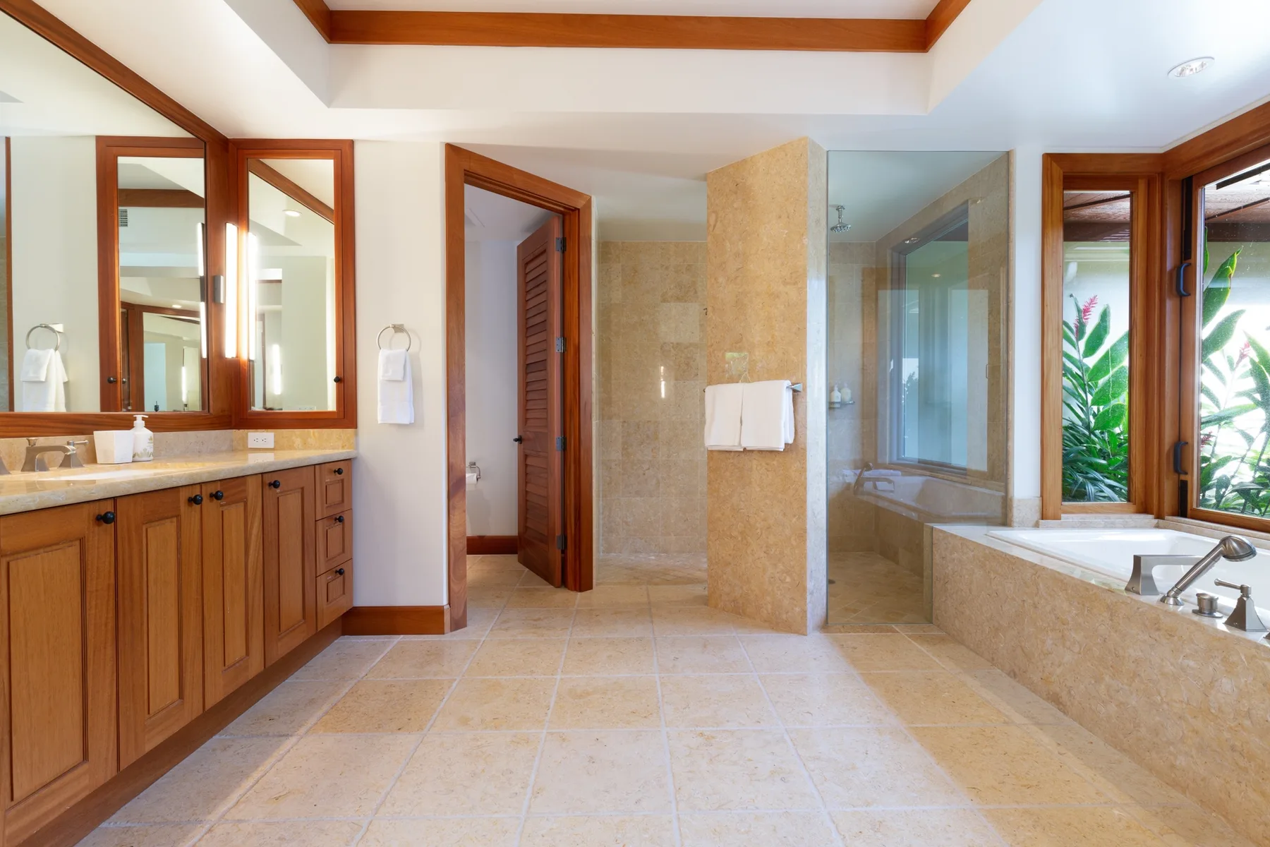A bright bathroom with a long vanity, glass shower, and bathtub.