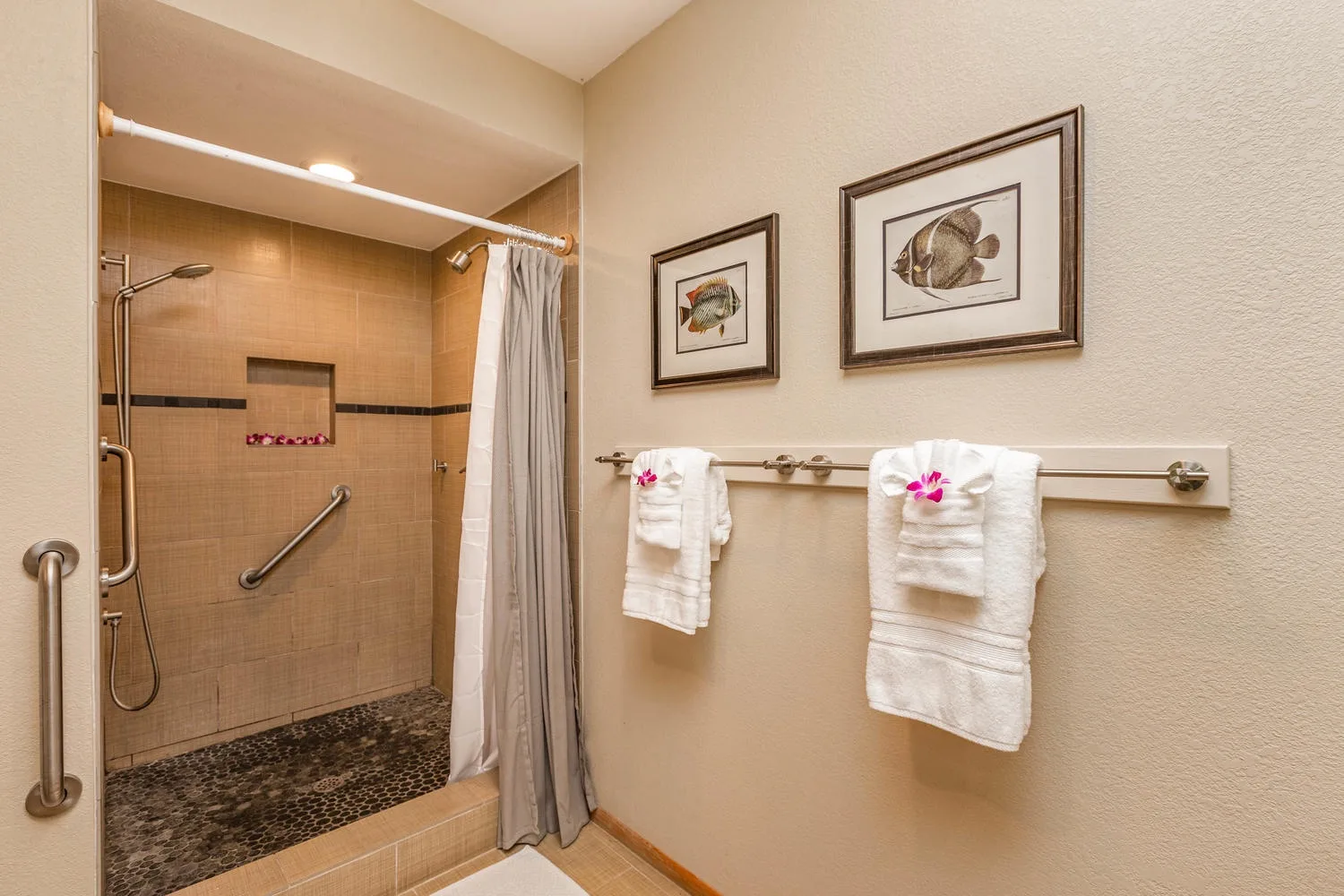 Un baño con una ducha revestida de azulejos y toallas colgadas en la pared.