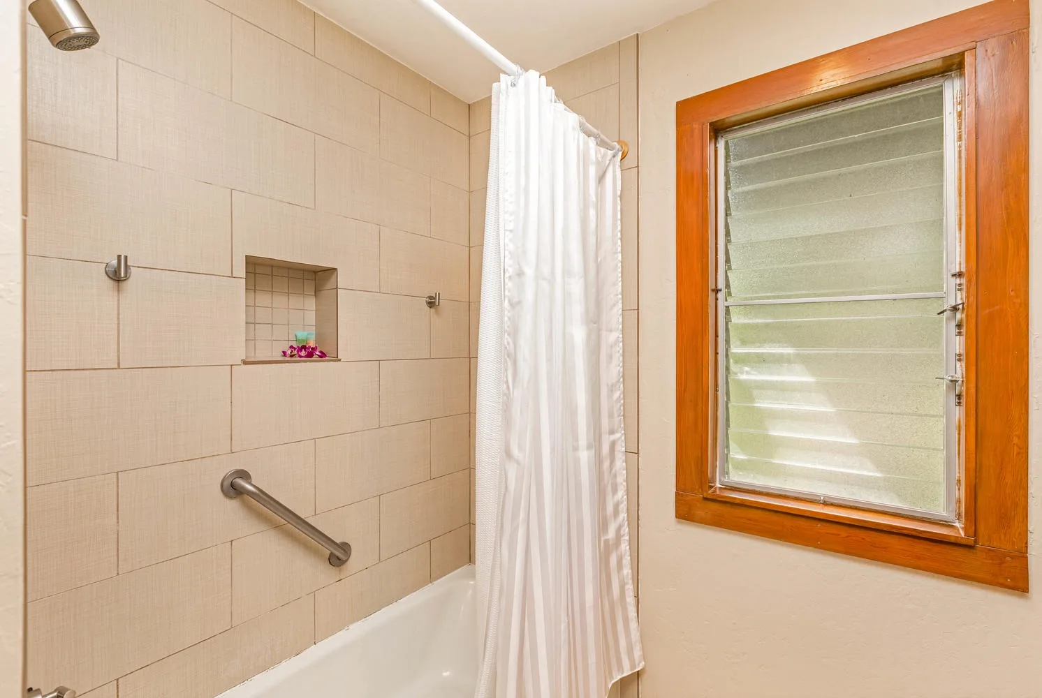 Un baño con azulejos, bañera, cortina de ducha y ventana.
