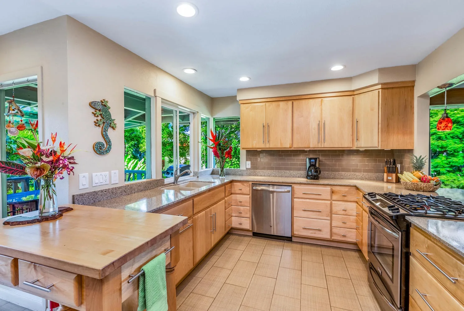 Una cocina luminosa con gabinetes de madera, piso de baldosas y ventanas con vista a la vegetación.