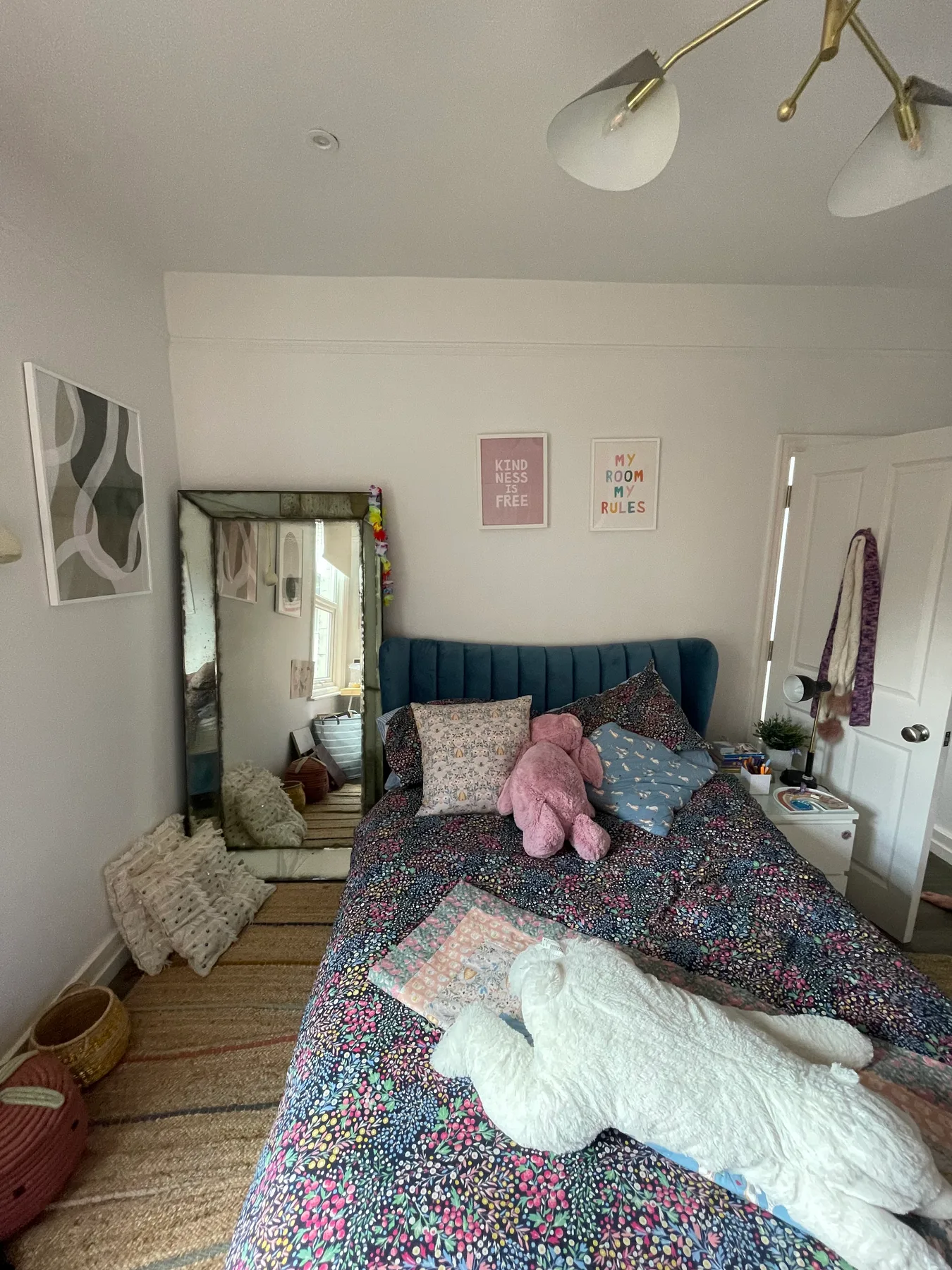 Un dormitorio con una colcha estampada y un espejo alto junto a la cama.
