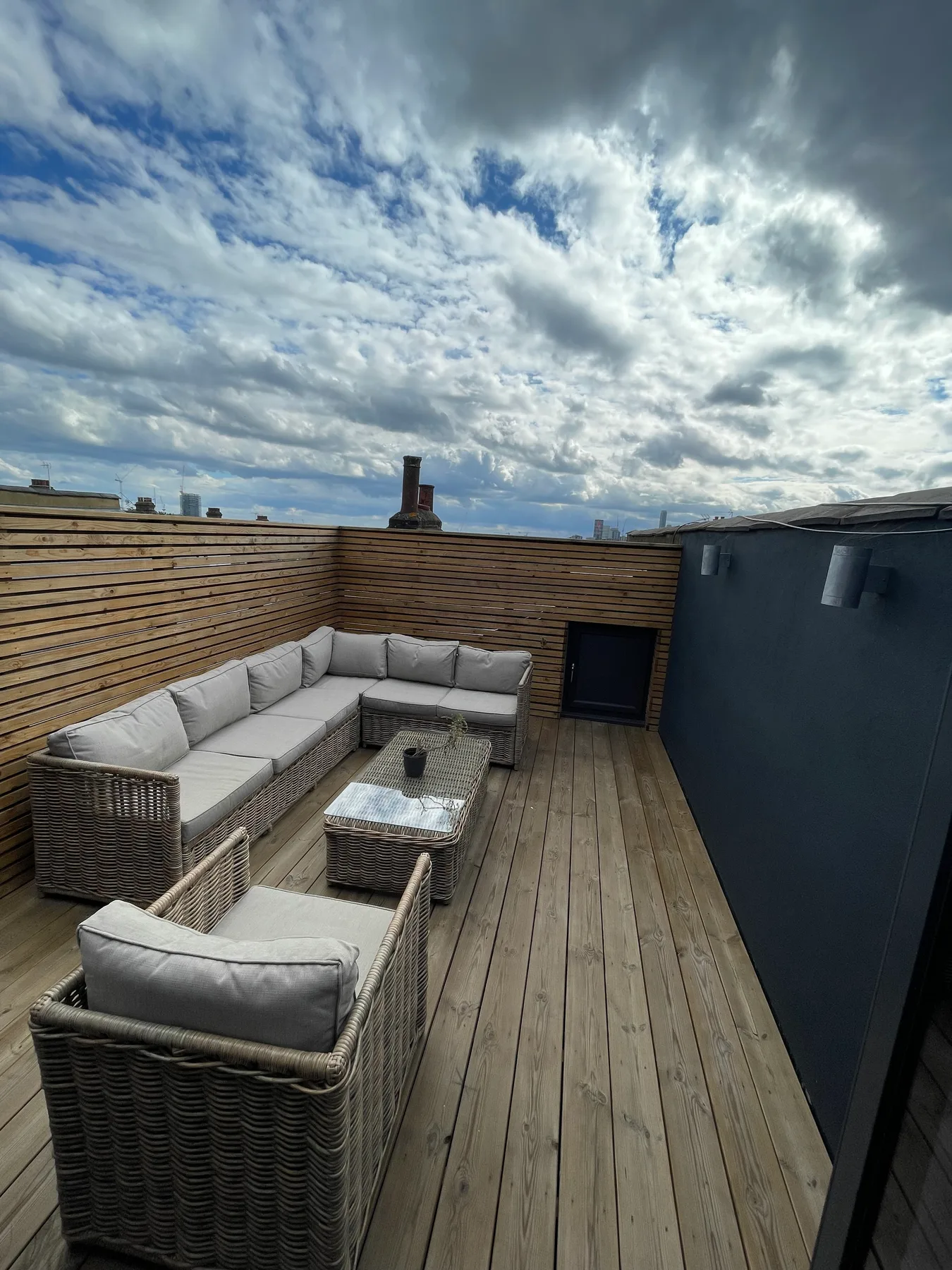 Una terraza exterior tiene una zona de asientos y una mesa baja.