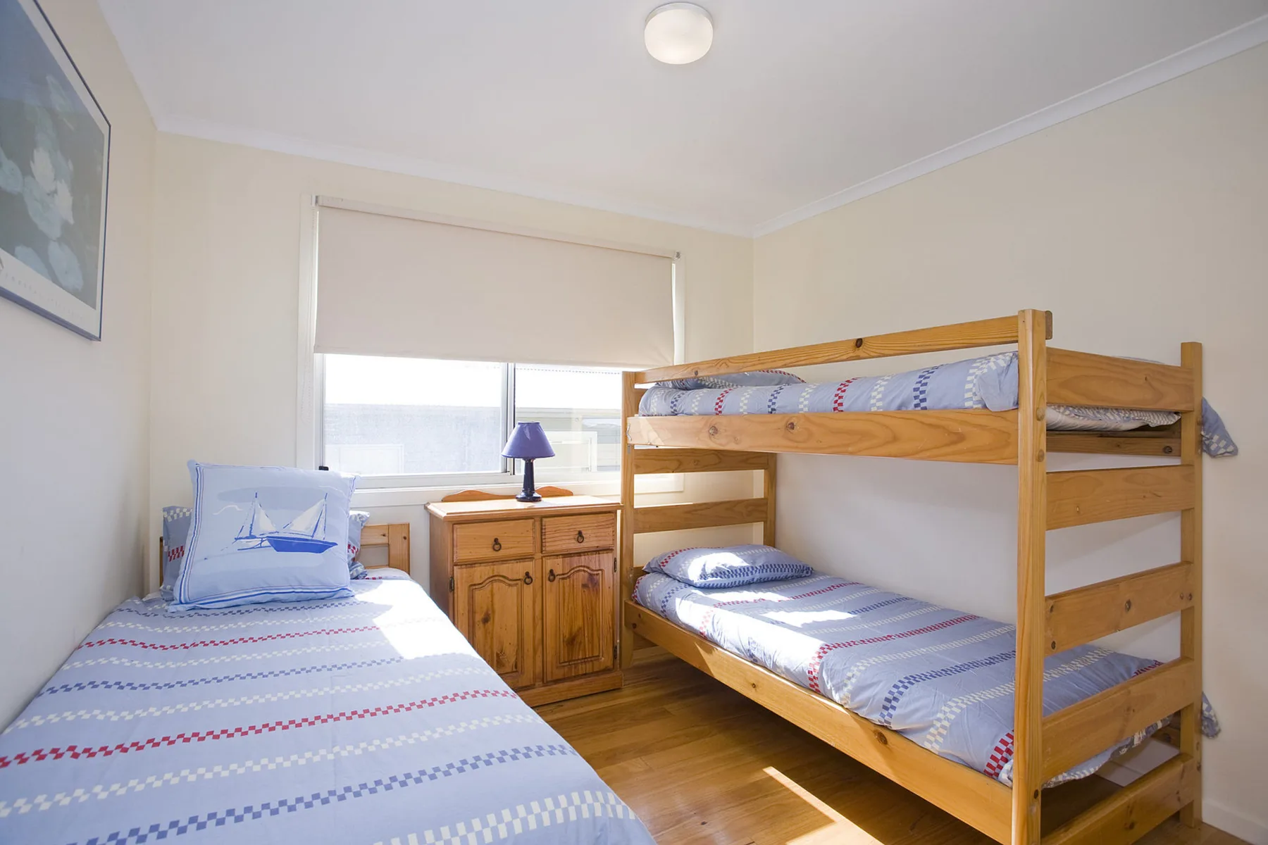 A bedroom with a single bed and a wooden bunk bed.