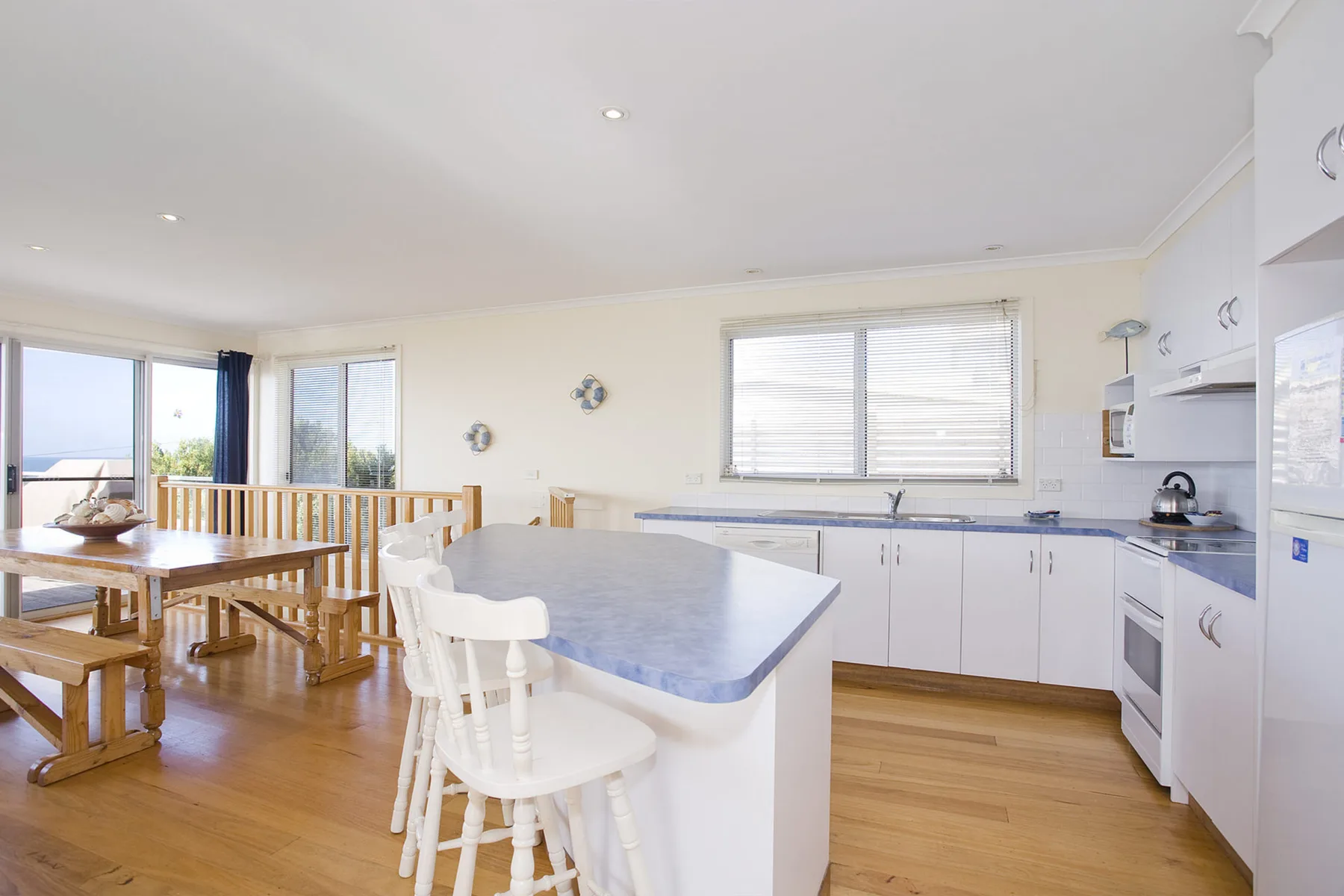 A bright kitchen with a central island and a wooden dining table.