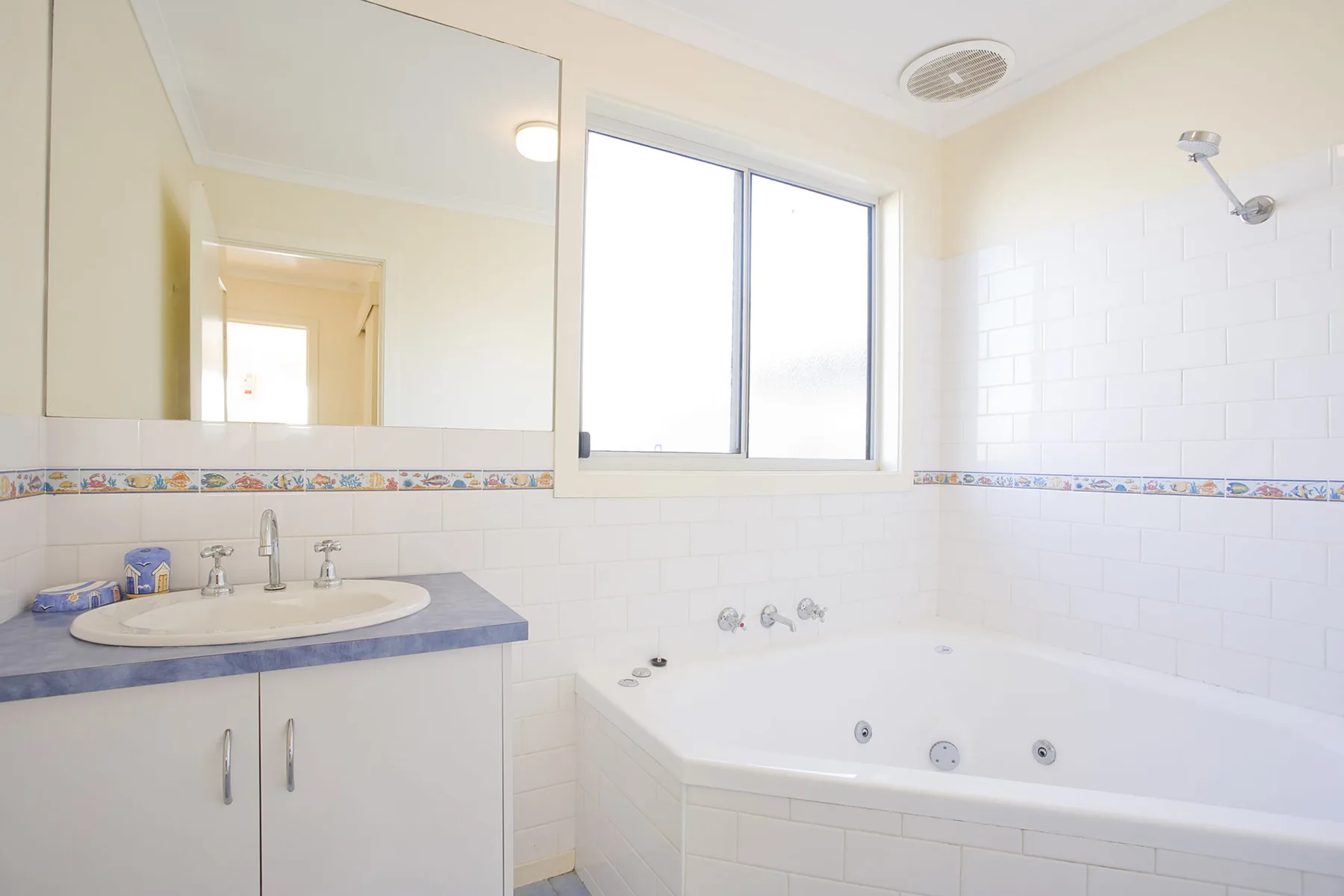 A bright bathroom with a bathtub and a sink beneath a large window.