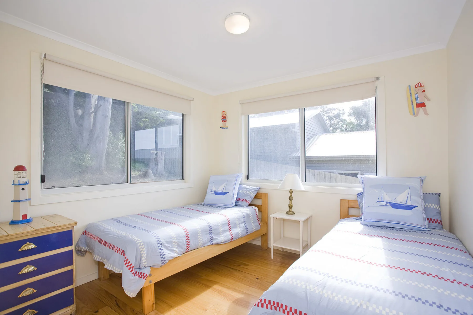 A twin bedroom with two beds beside large windows.