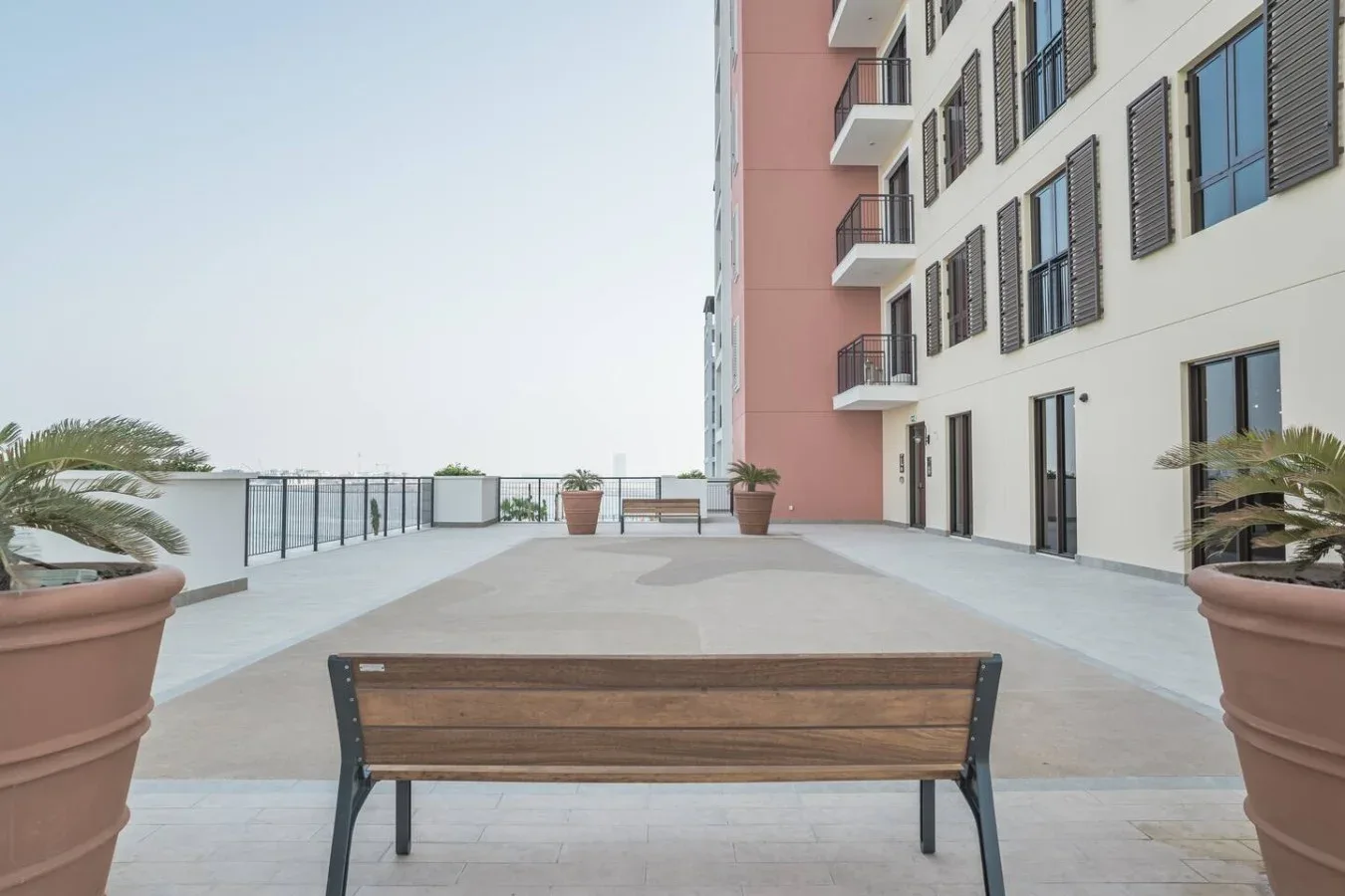 Una terraza al aire libre con un banco de madera junto a un edificio de varias plantas.