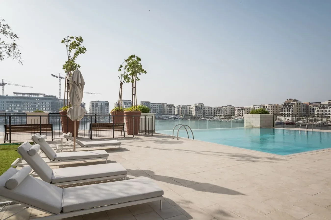 Una terraza con piscina y tumbonas ofrece vistas al agua y a los edificios cercanos.