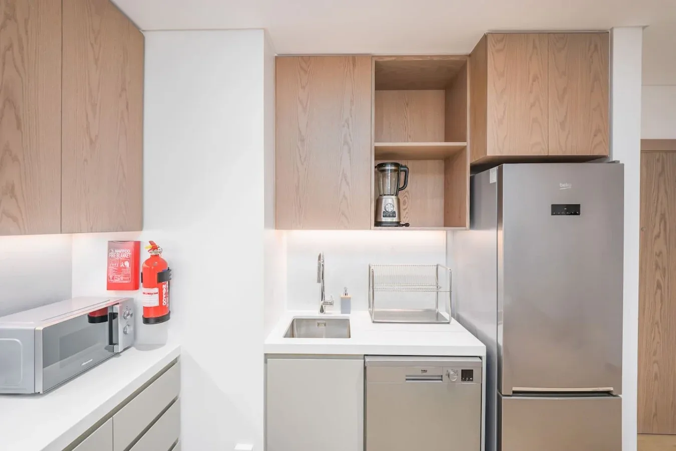 Una cocina compacta con armarios de madera, un microondas sobre la encimera y un refrigerador.