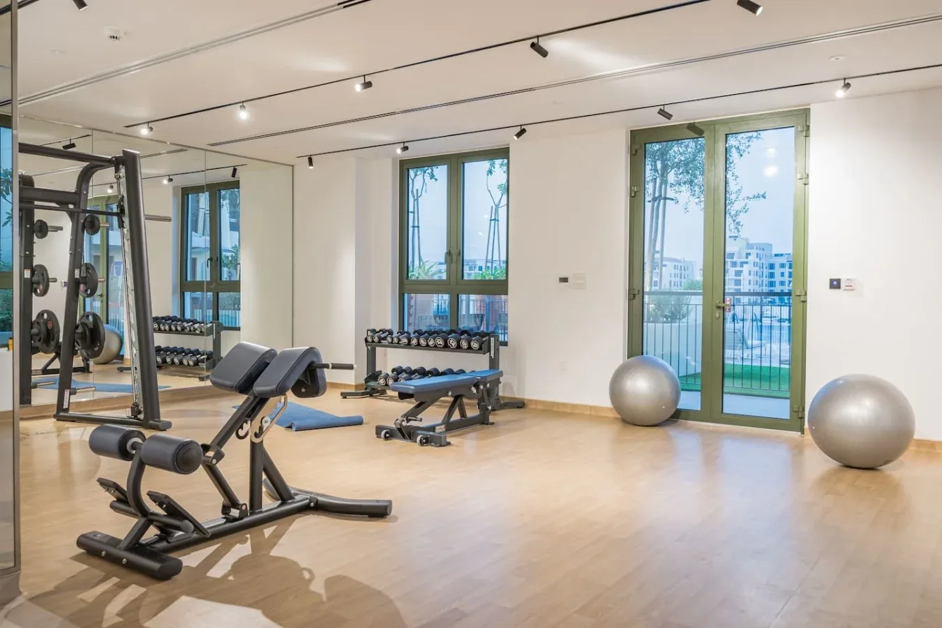 Un gimnasio luminoso con máquinas de pesas, bancos de ejercicio y grandes ventanas.