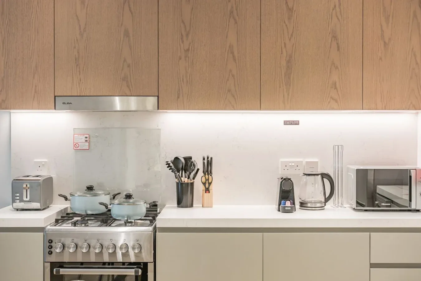 Una cocina moderna con fogón, utensilios y electrodomésticos sobre la encimera.
