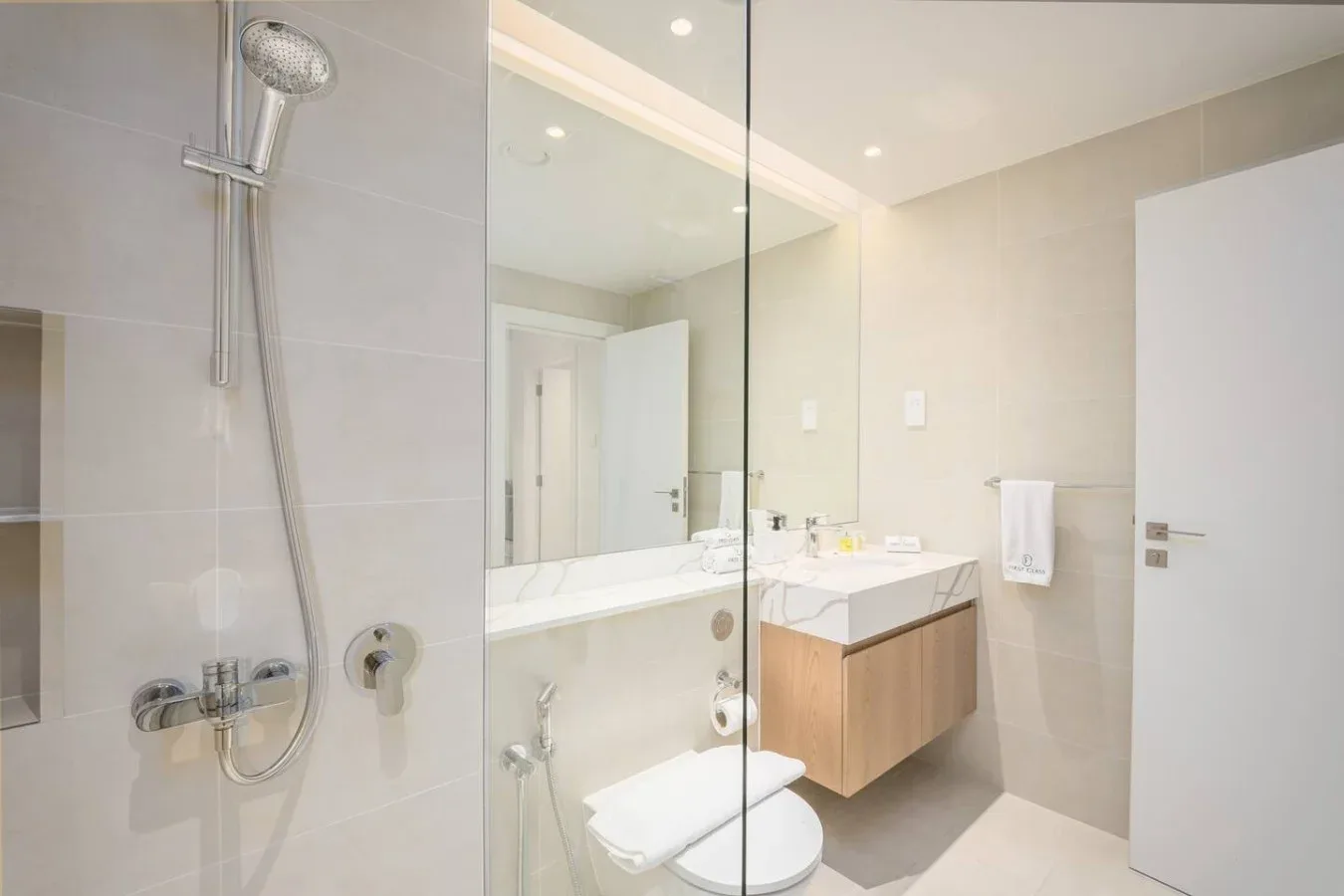 Un baño luminoso con ducha de vidrio, lavabo y sanitario.