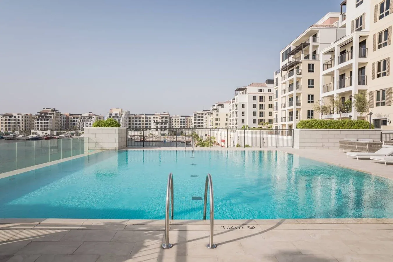 Una piscina al aire libre da a un complejo residencial junto al agua.