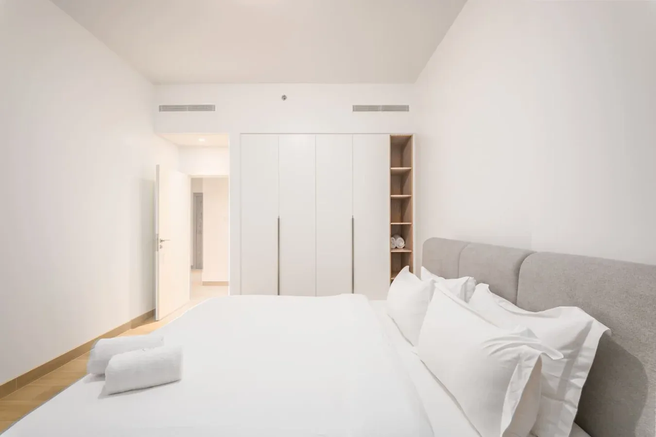 Un dormitorio luminoso con una cama blanca y armarios empotrados.