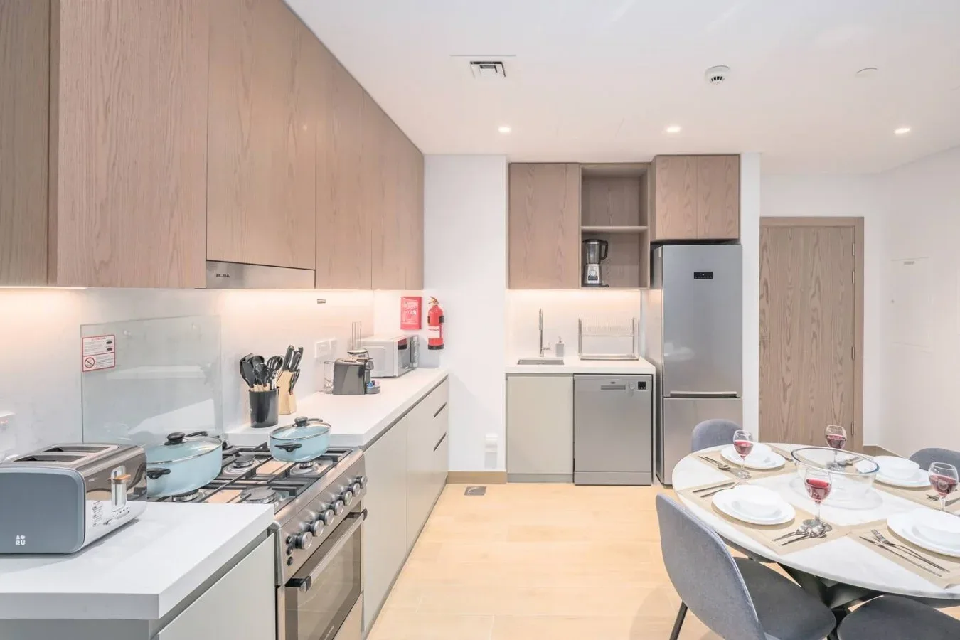 Una cocina moderna con gabinetes claros, electrodomésticos de cocina y una mesa de comedor.