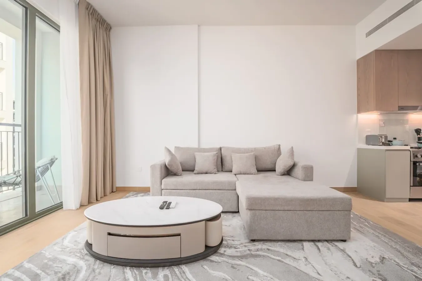 Una sala luminosa con asientos junto a una mesa de centro redonda y ventanales.