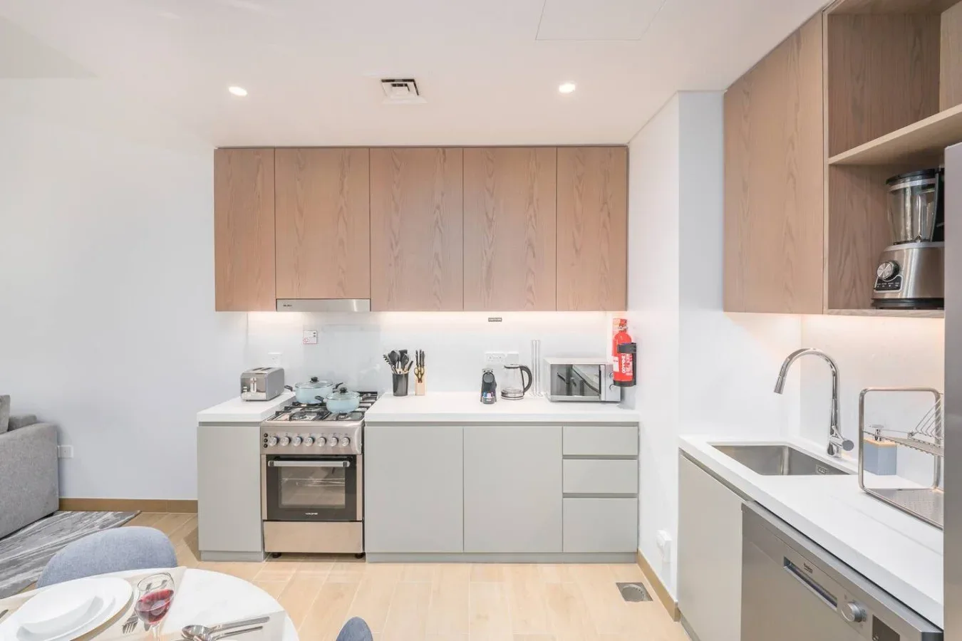 Una cocina moderna y luminosa con gabinetes de madera clara y una encimera blanca.