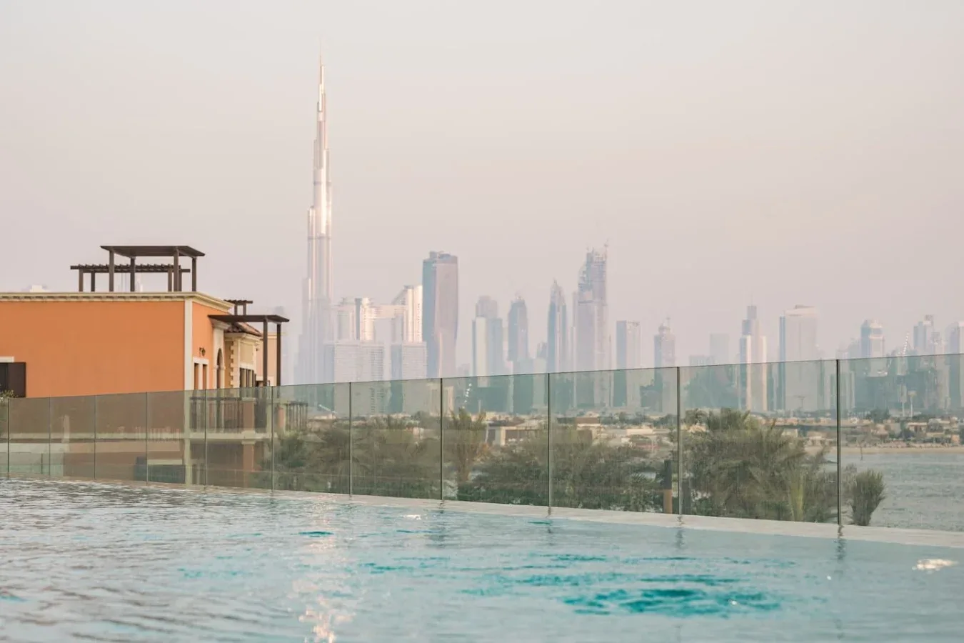 Una piscina en la azotea ofrece vistas del horizonte de la ciudad tras una barandilla de vidrio.