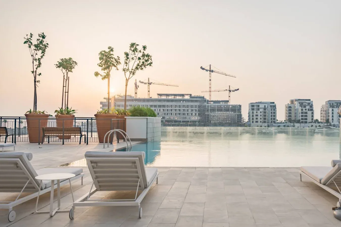 Una terraza con piscina en la azotea da a edificios junto al agua, con asientos de descanso.