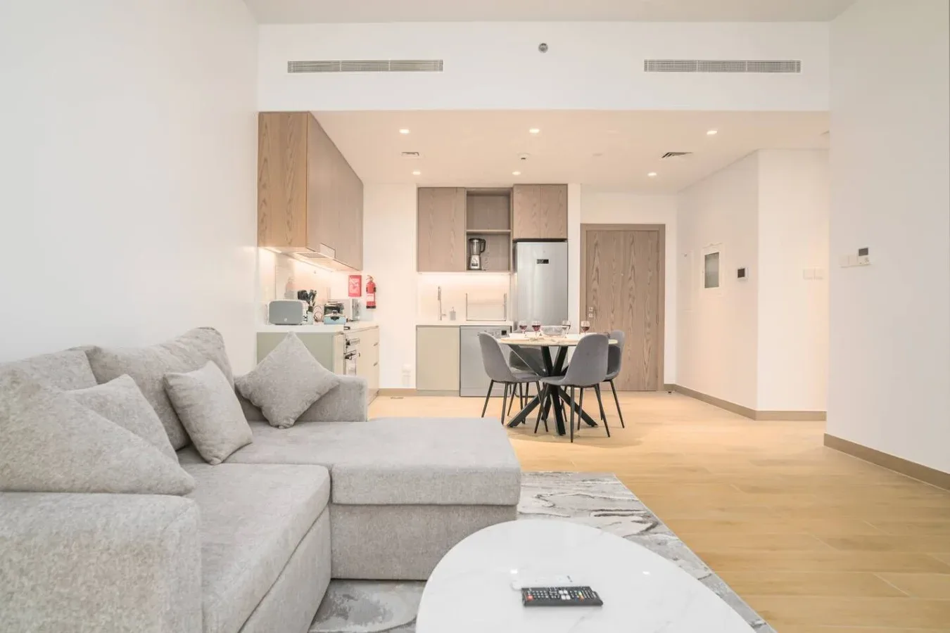 Una luminosa sala-comedor diáfana con asientos grises y una mesa de comedor.
