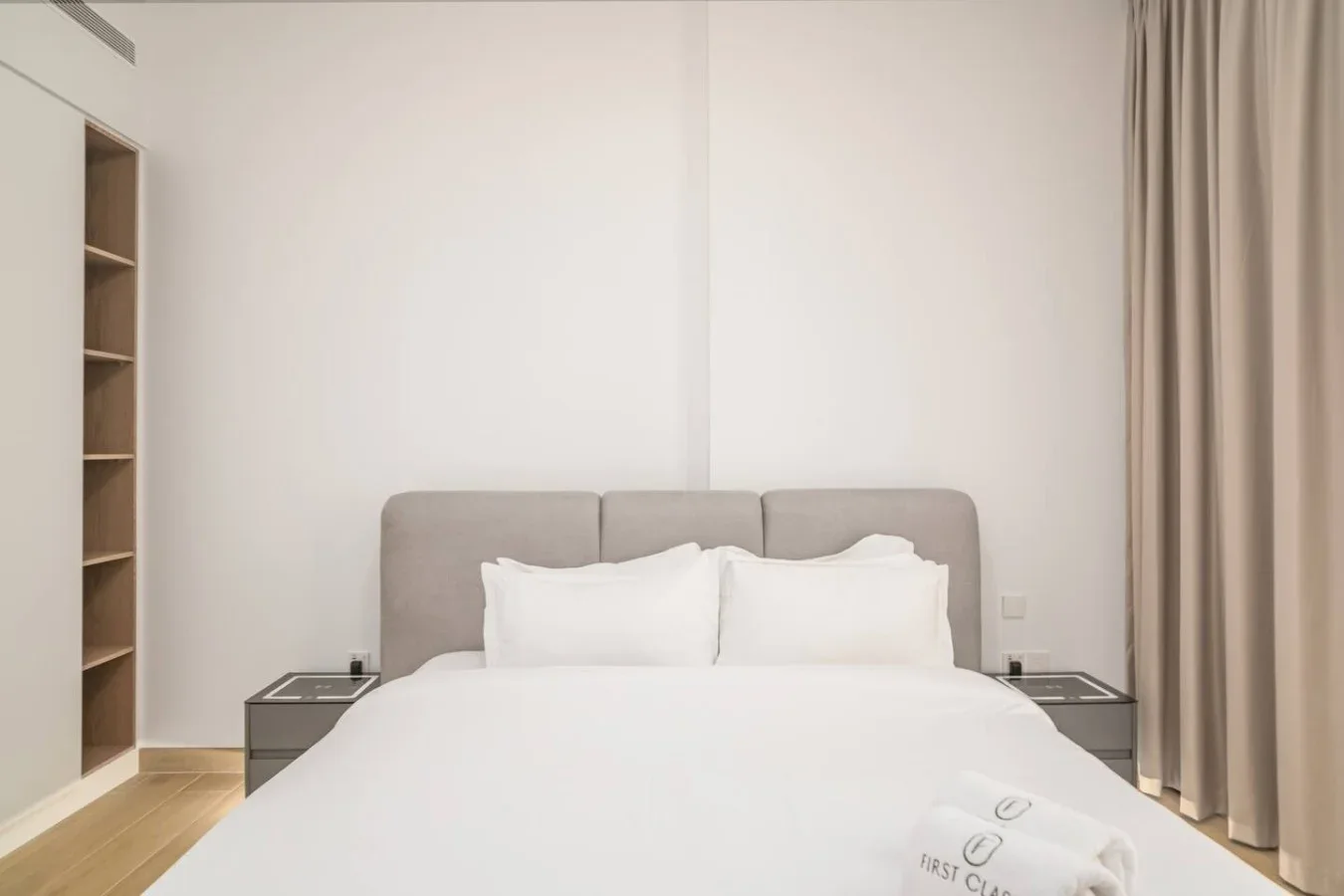 Un dormitorio con una cama bien tendida, mesitas de noche y cortinas.