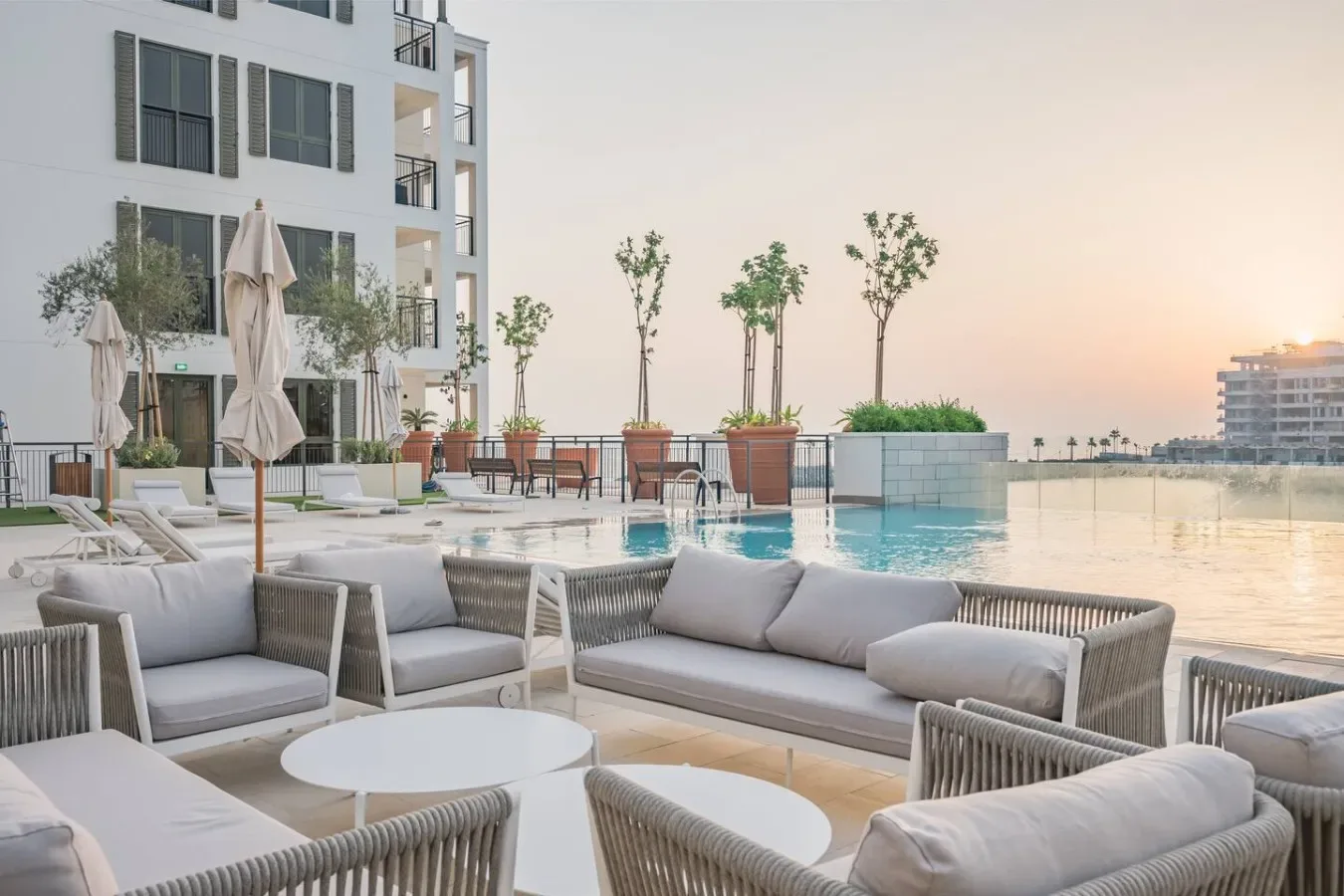 Una terraza con piscina y asientos al aire libre mira hacia el agua al atardecer.