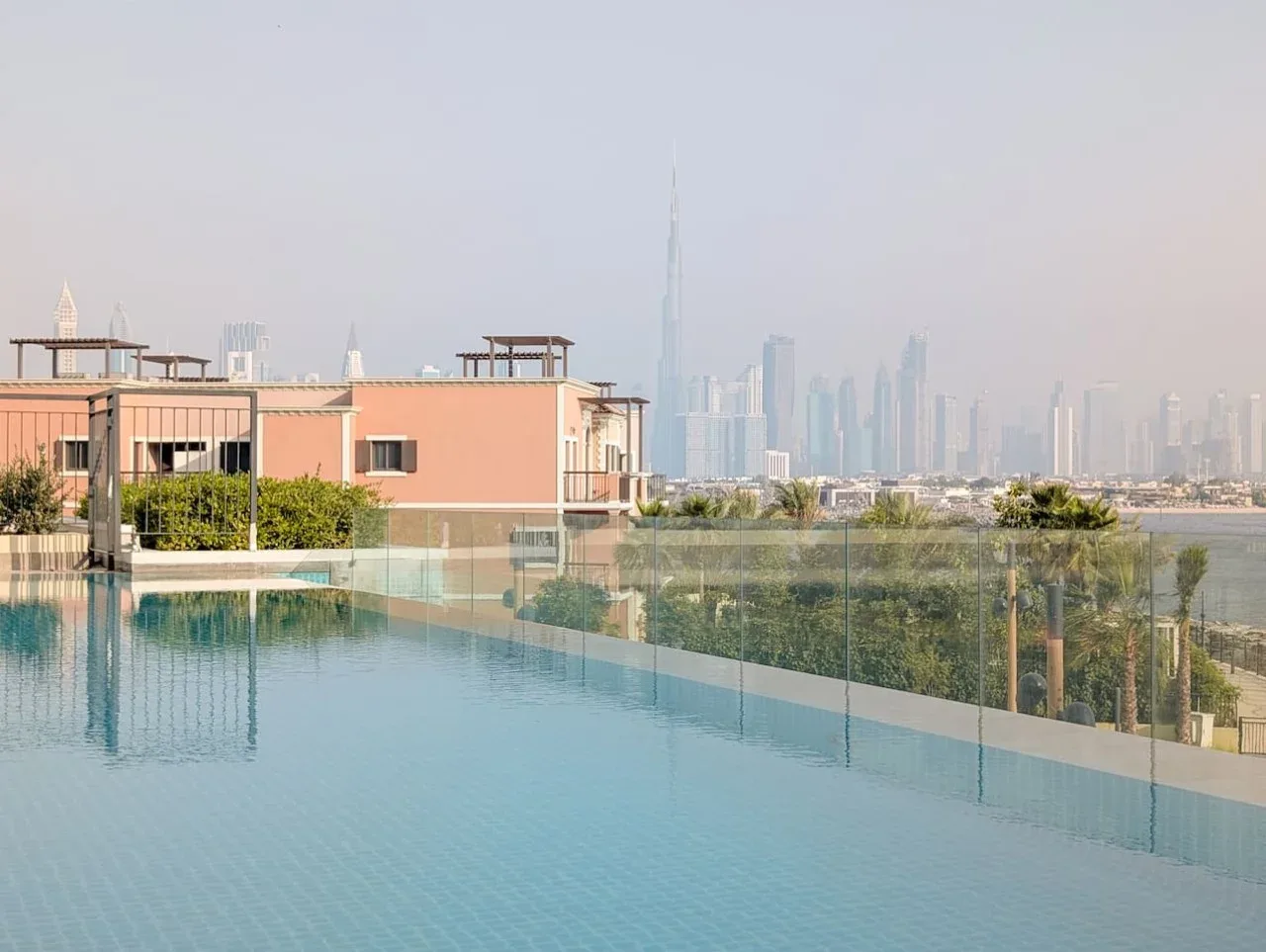 Una piscina en la azotea tiene vistas a un horizonte urbano brumoso.