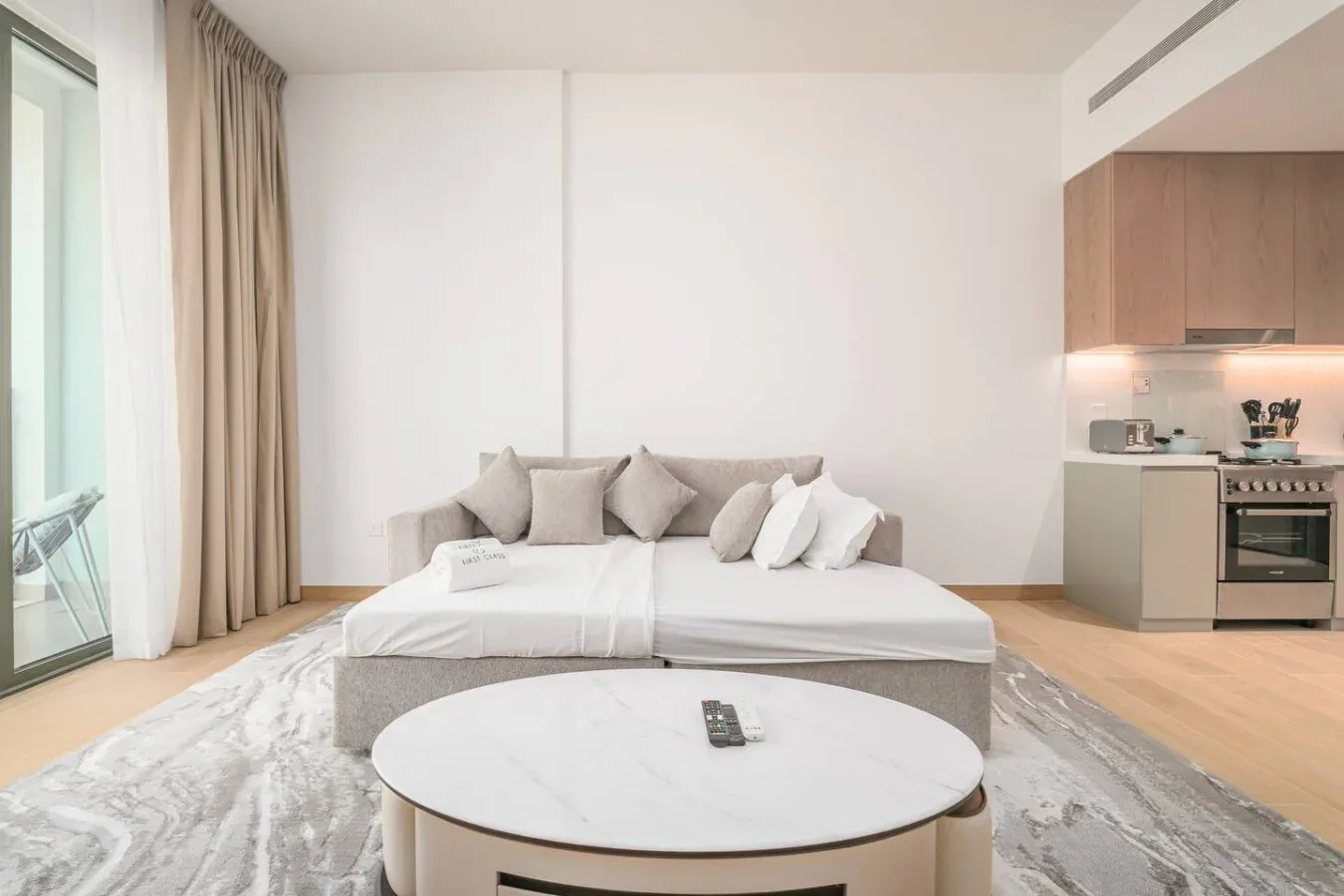 Un dormitorio con una cama, una mesa de centro redonda y una pequeña cocina.