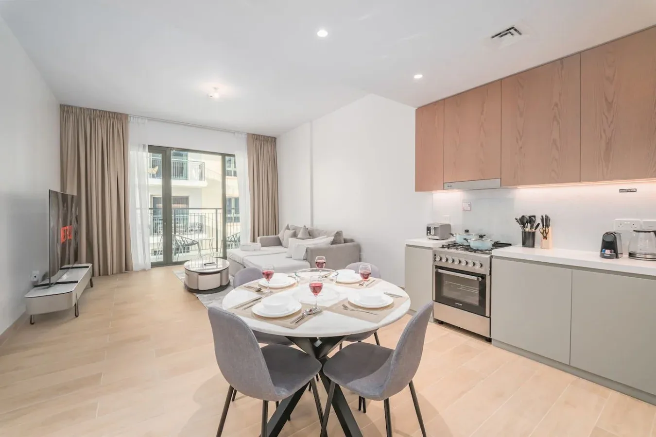 Una sala-comedor de planta abierta con cocina y puertas al balcón.