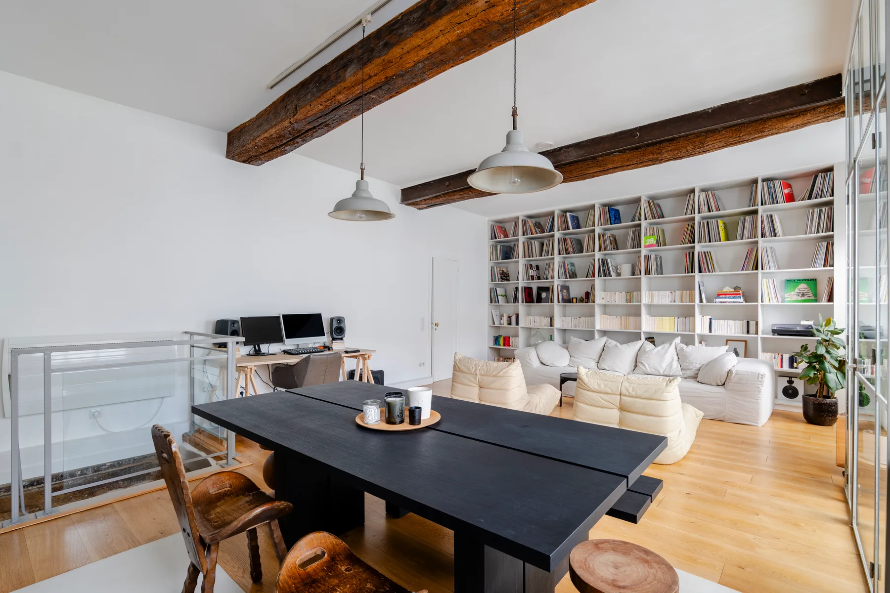 Una luminosa sala de estar y comedor tiene una mesa larga, asientos y estanterías.