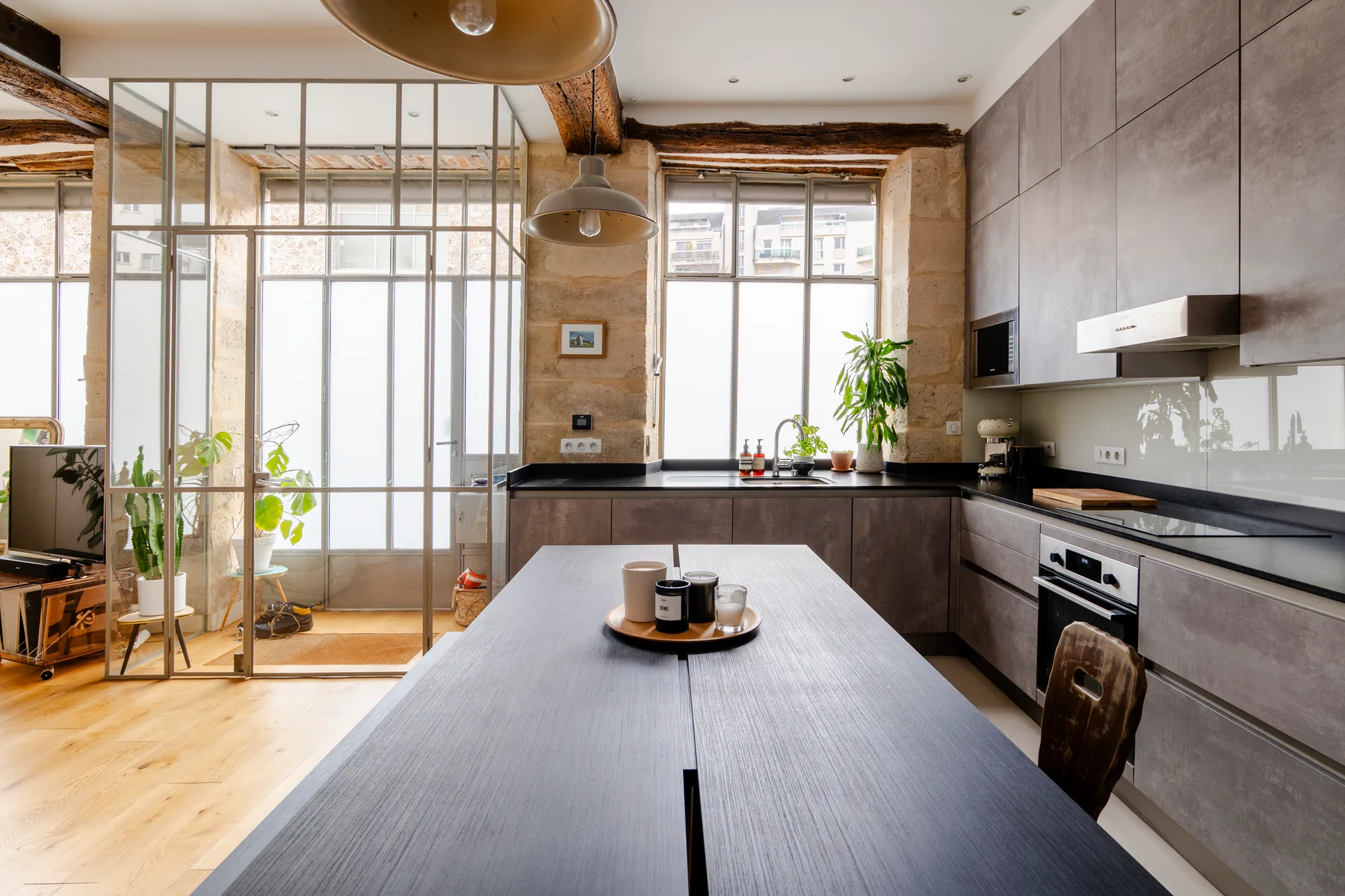 Una cocina moderna y zona de comedor con una mesa larga y grandes ventanas.