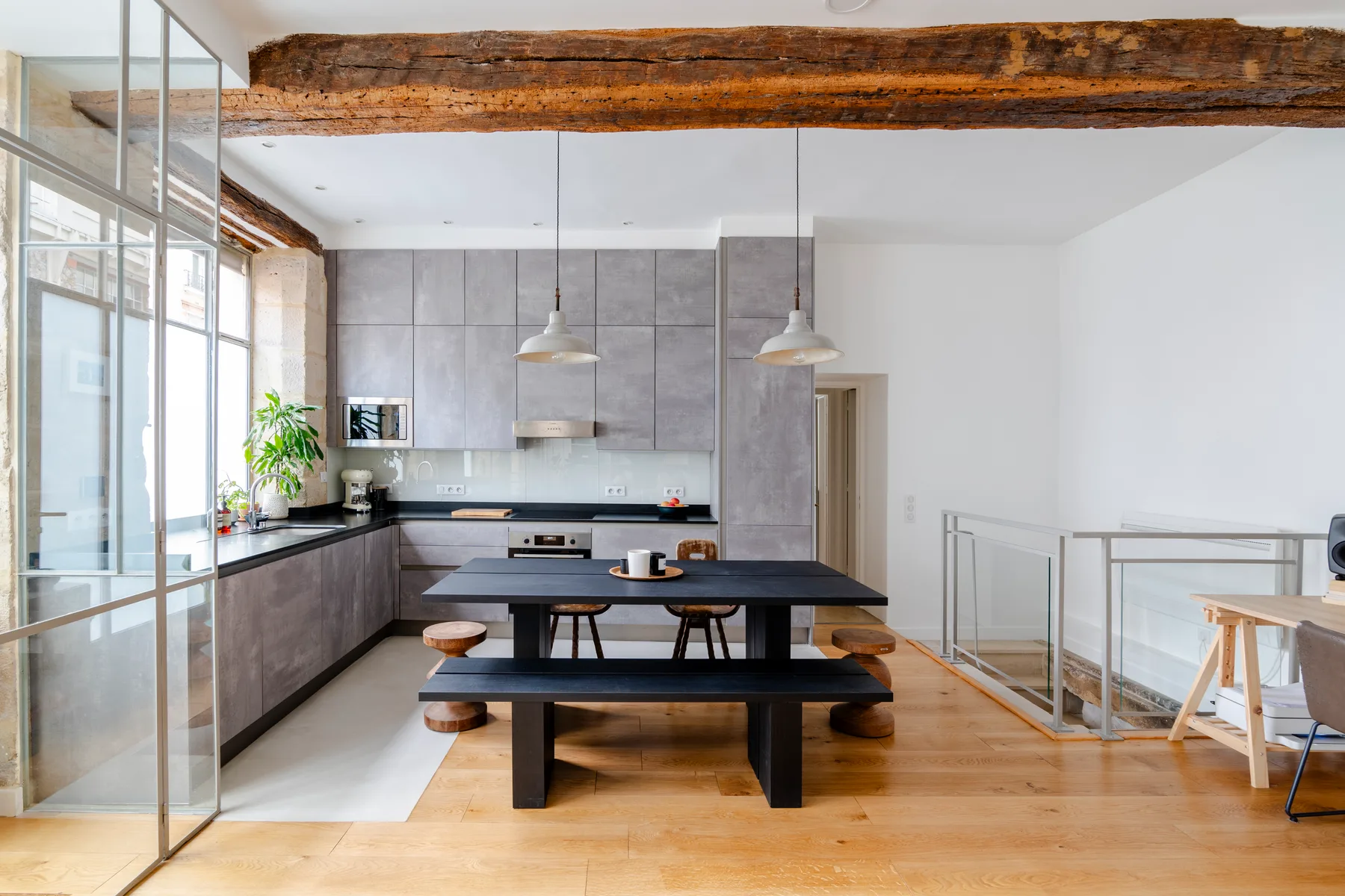 Una cocina moderna con comedor y una mesa larga bajo vigas de techo expuestas.