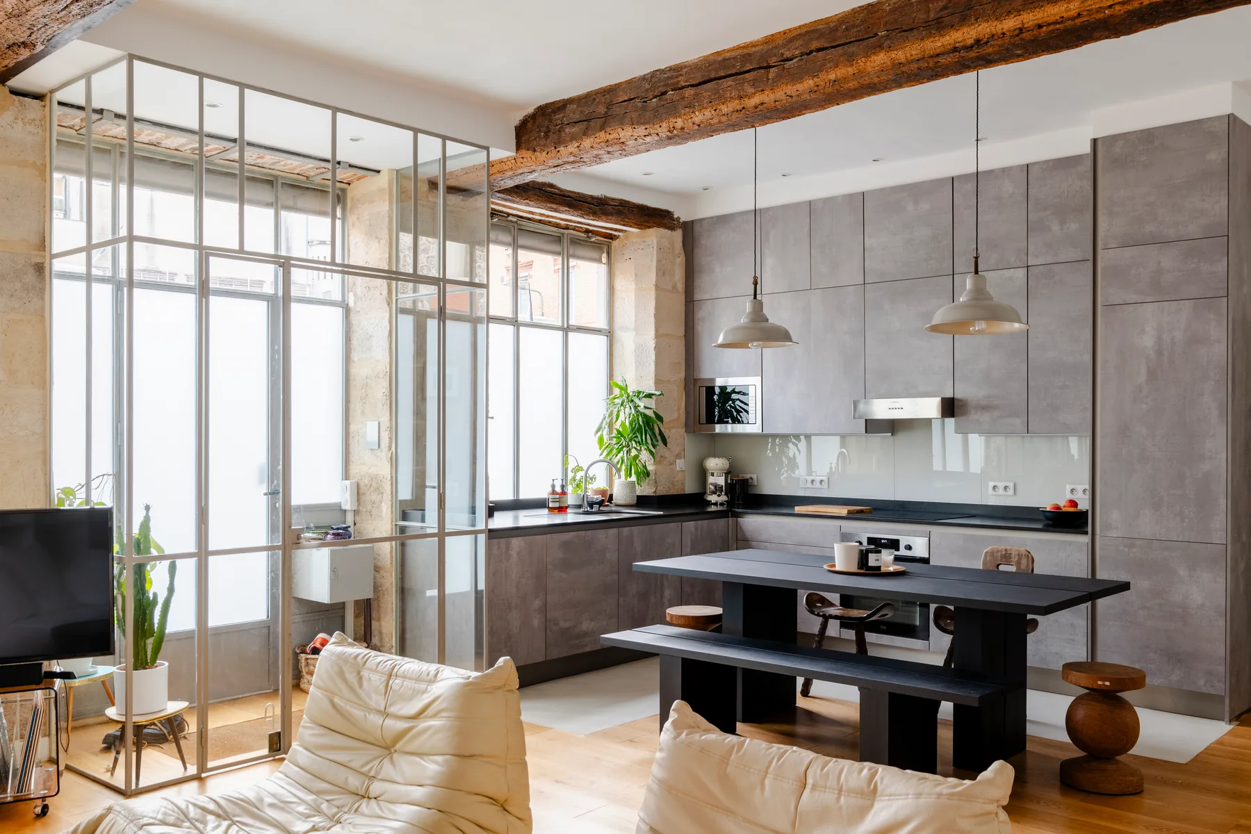 Una cocina y comedor modernos, con grandes ventanales y una mesa central.