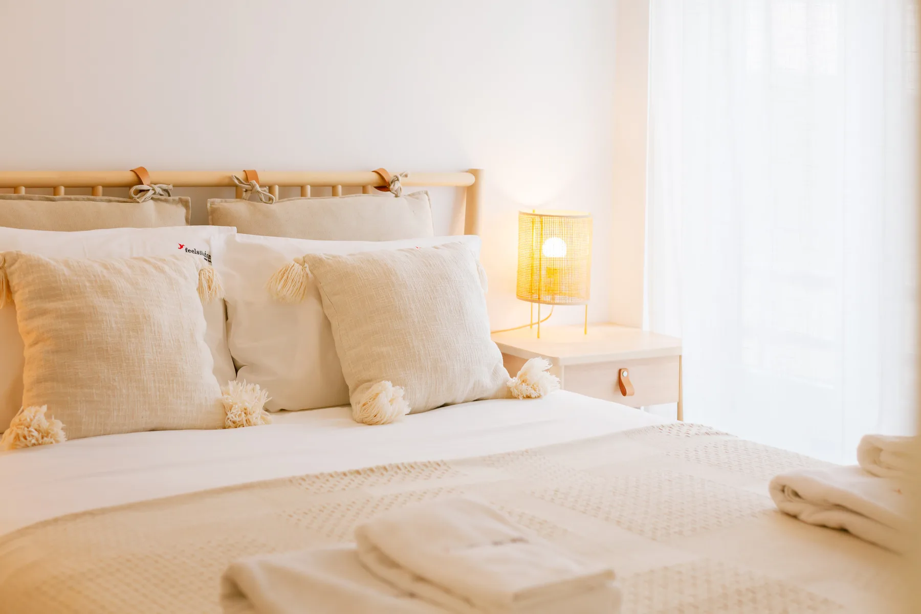 Un dormitorio luminoso con una cama bien tendida y una lámpara encendida junto a ella.
