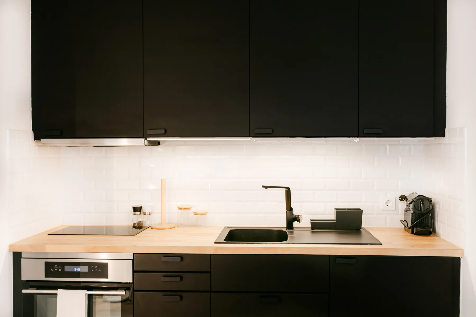 Una cocina moderna con gabinetes oscuros, una placa de cocina y un horno integrado.