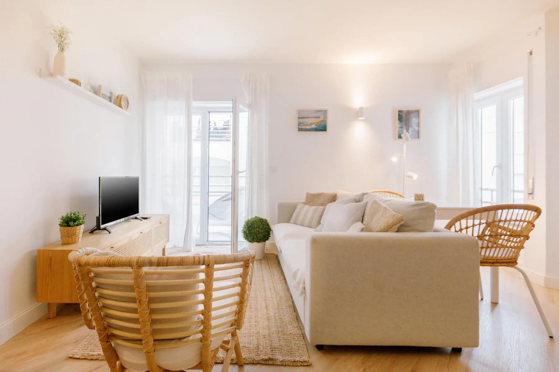 Una sala de estar luminosa con sofá, televisor y asientos tejidos.