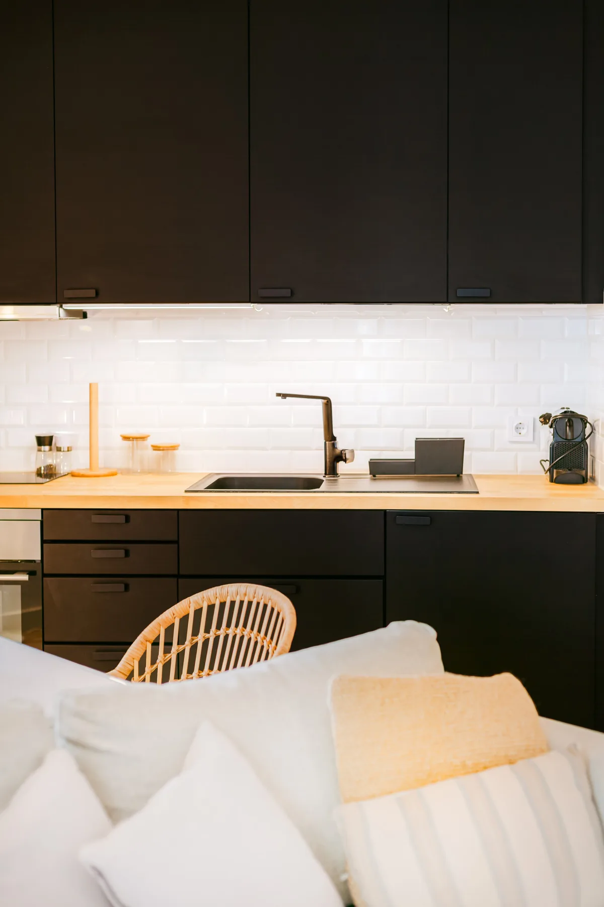 Una cocina moderna con fregadero y armarios oscuros detrás de una zona de estar.