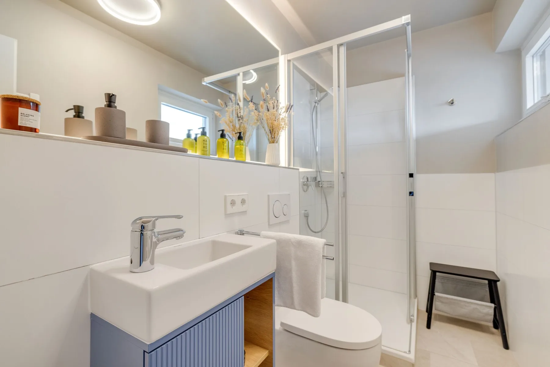 Un baño luminoso con lavabo, inodoro y ducha de vidrio.