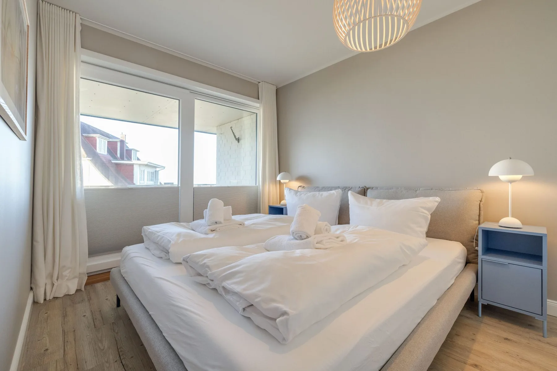 Un dormitorio con una cama grande junto a una ventana con cortinas.