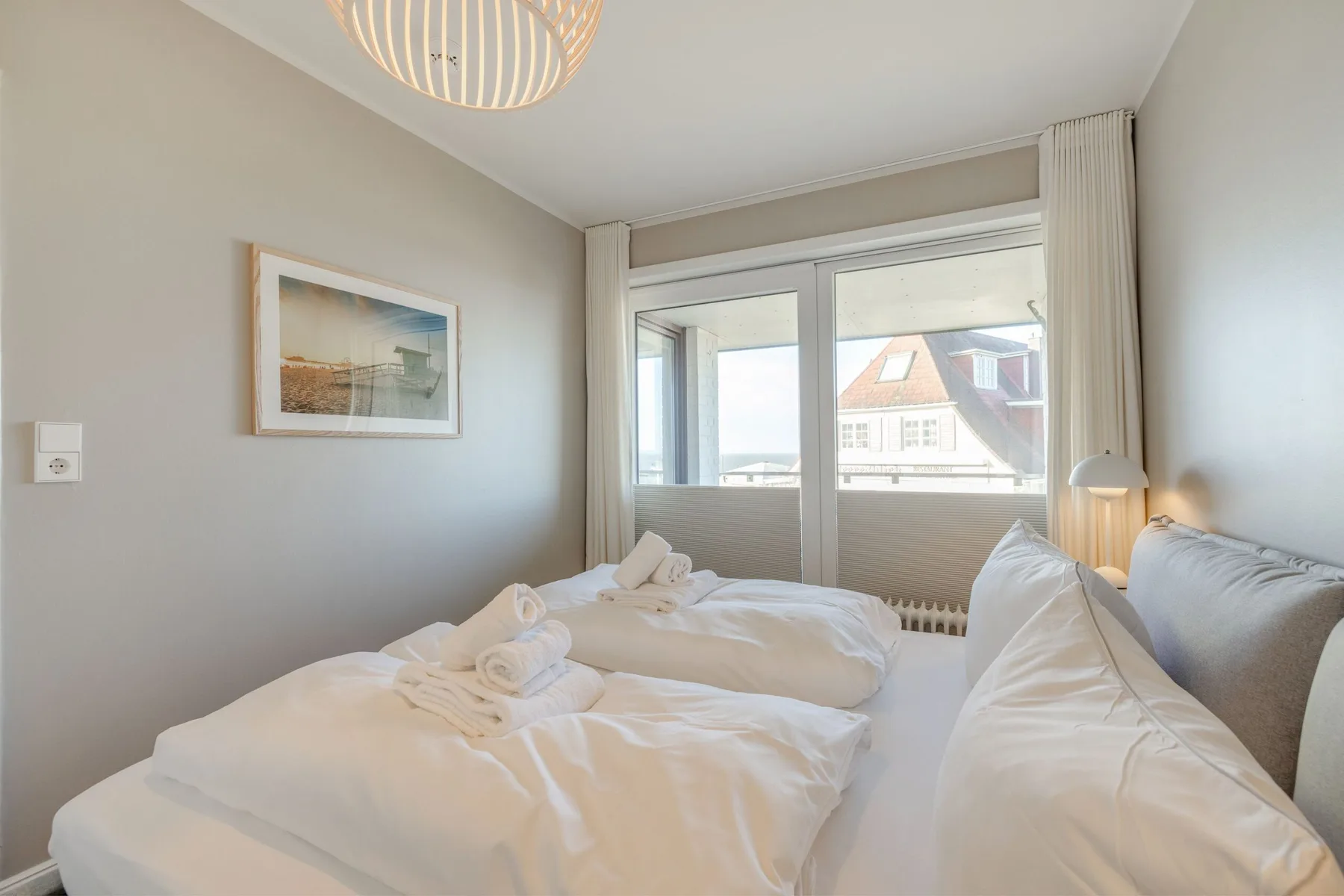 Un dormitorio luminoso con ropa de cama blanca y una ventana grande.