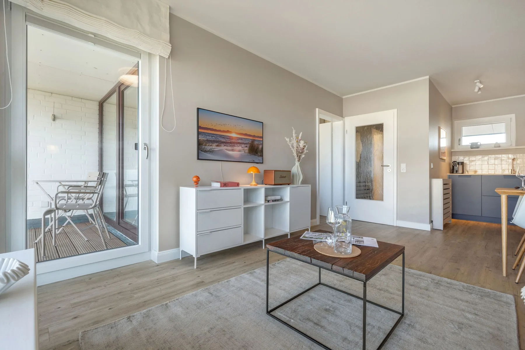 Una sala de estar con mesa de centro, mueble bajo y puertas corredizas de vidrio.