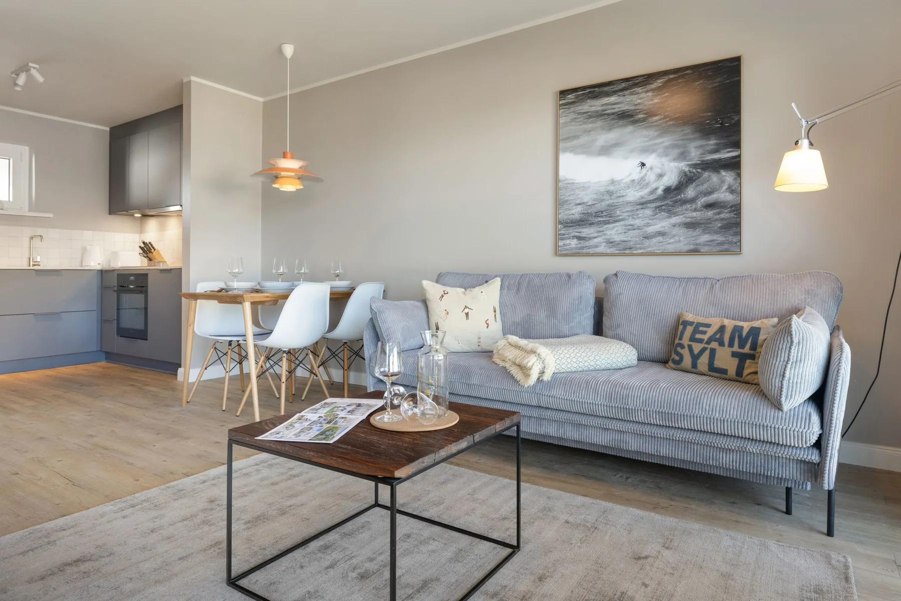 Una sala de estar con sofá, mesa de centro y comedor junto a la cocina.