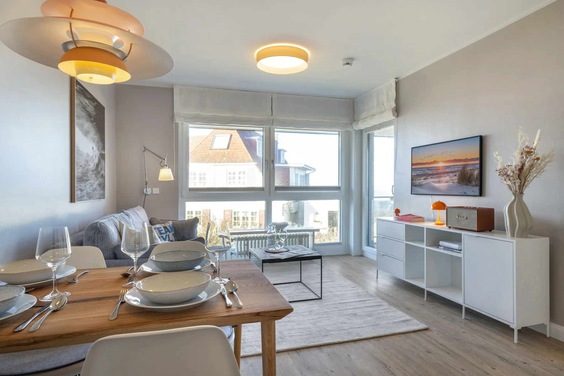 Una luminosa sala de estar y comedor con una ventana grande y una mesa puesta.