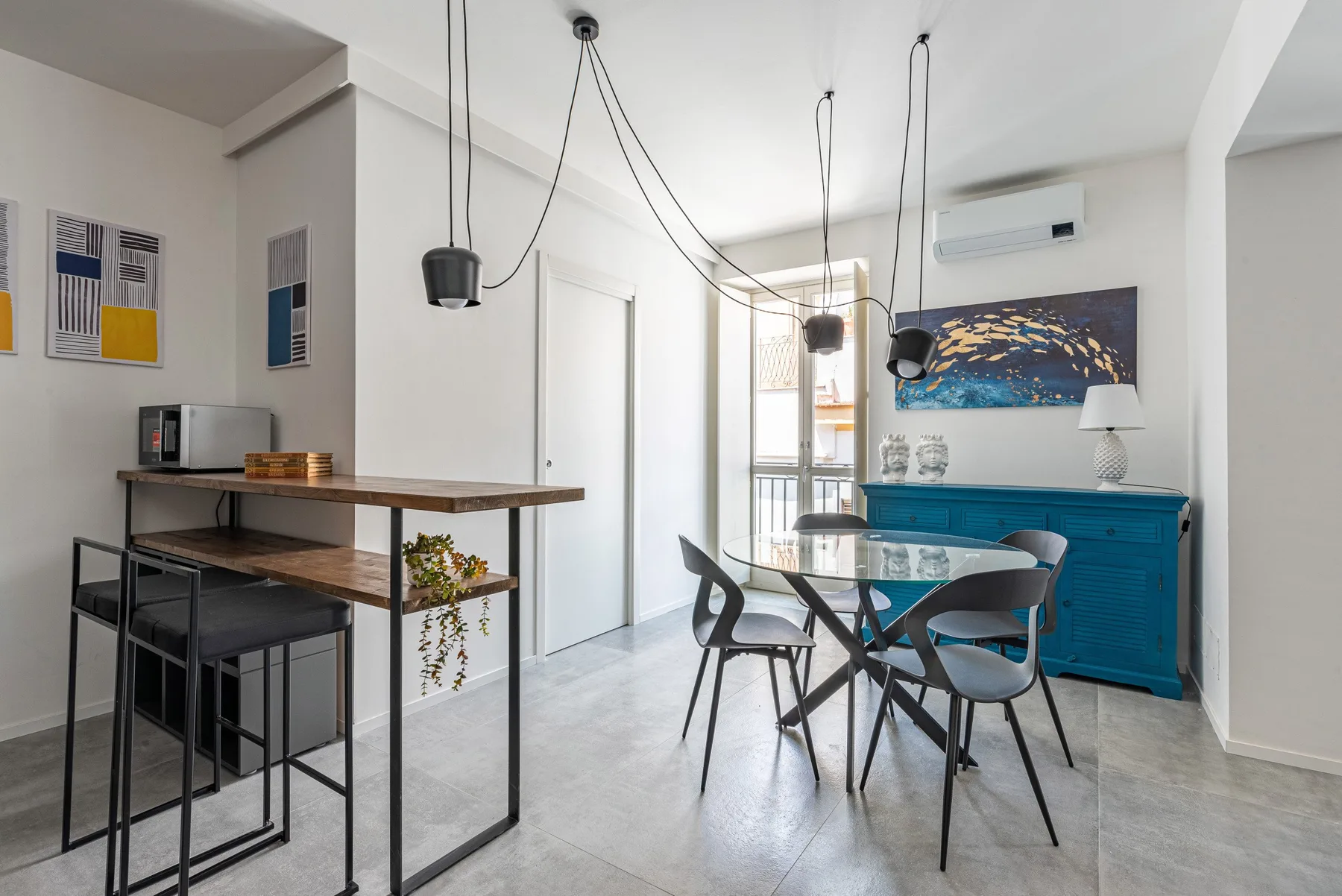 Comedor con una mesa de vidrio, sillas y un aparador azul.