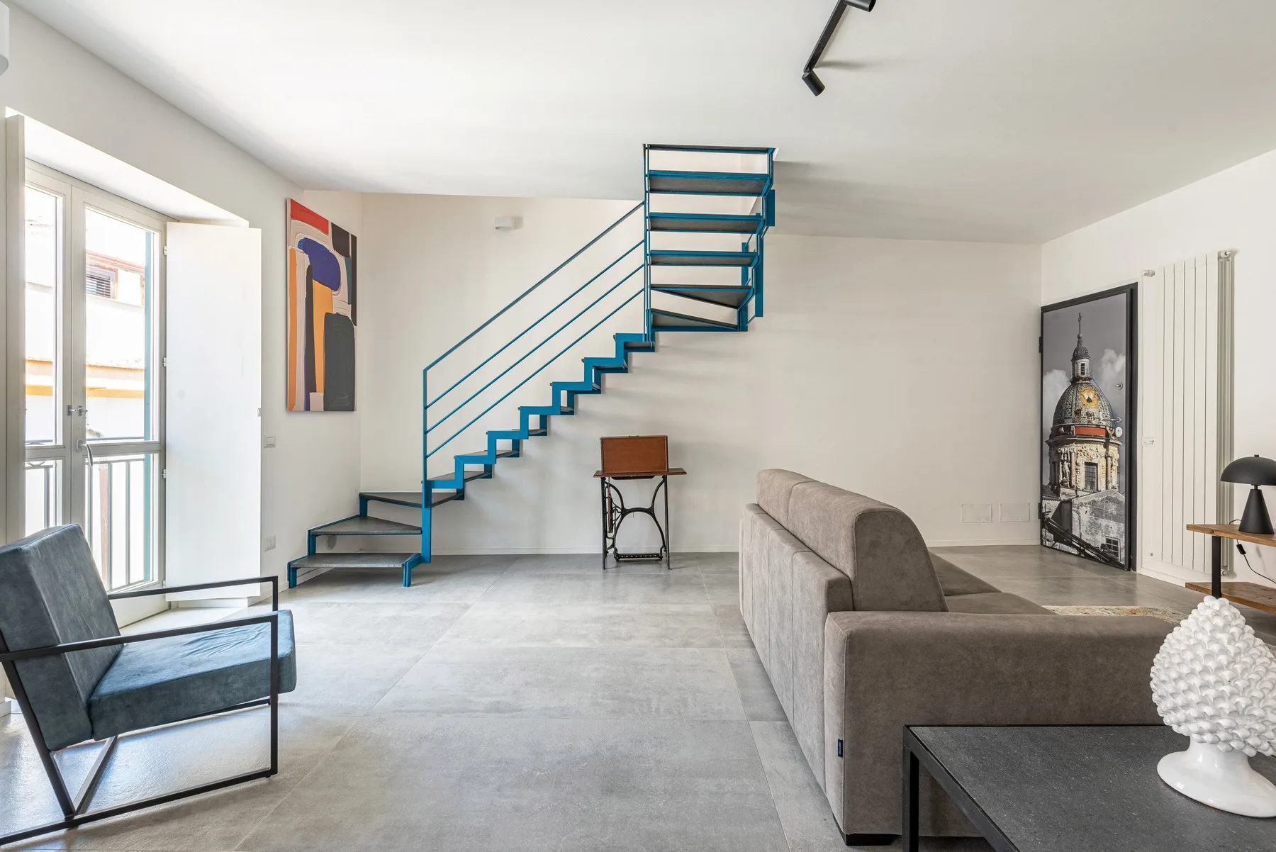 Una sala luminosa con una escalera y asientos junto a grandes ventanas.