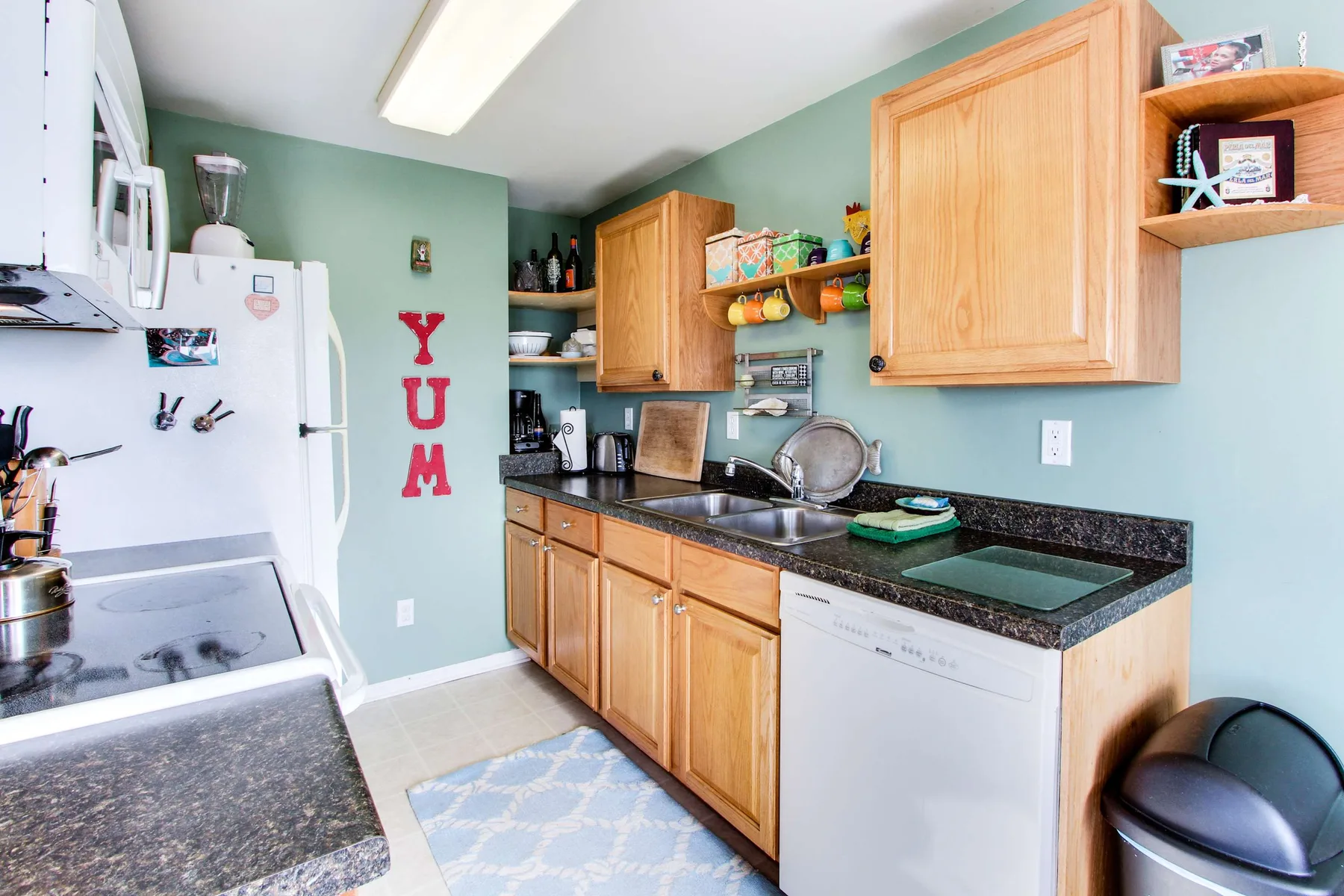 Una cocina con gabinetes de madera, encimeras oscuras y un refrigerador blanco.