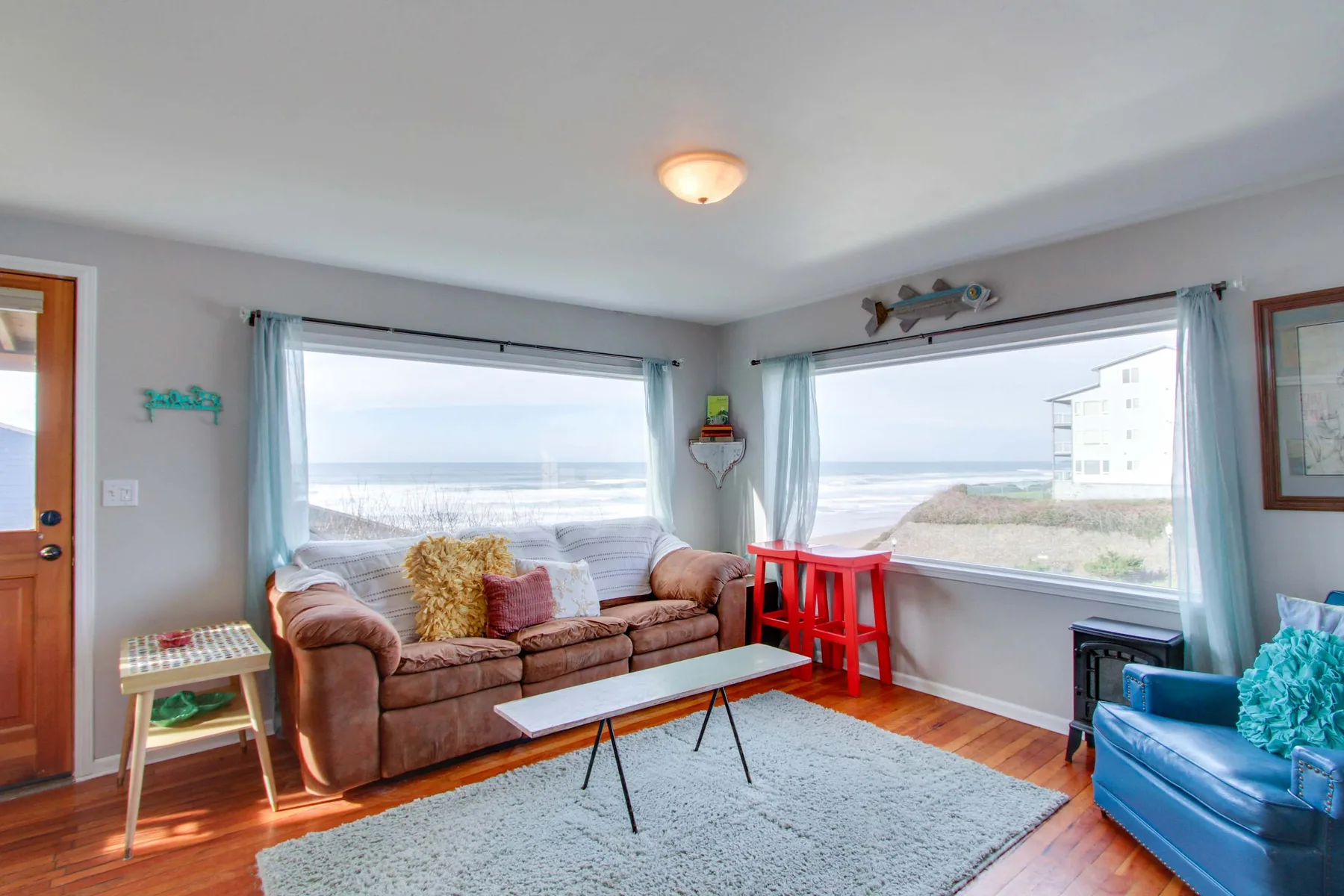 A bright living room with seating beside large windows overlooking the ocean.