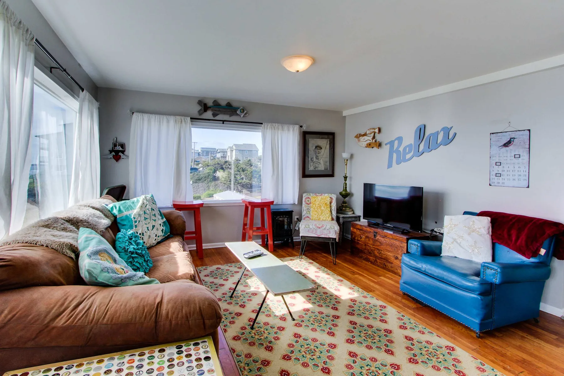 A bright living room with seating, a television, and a large window.