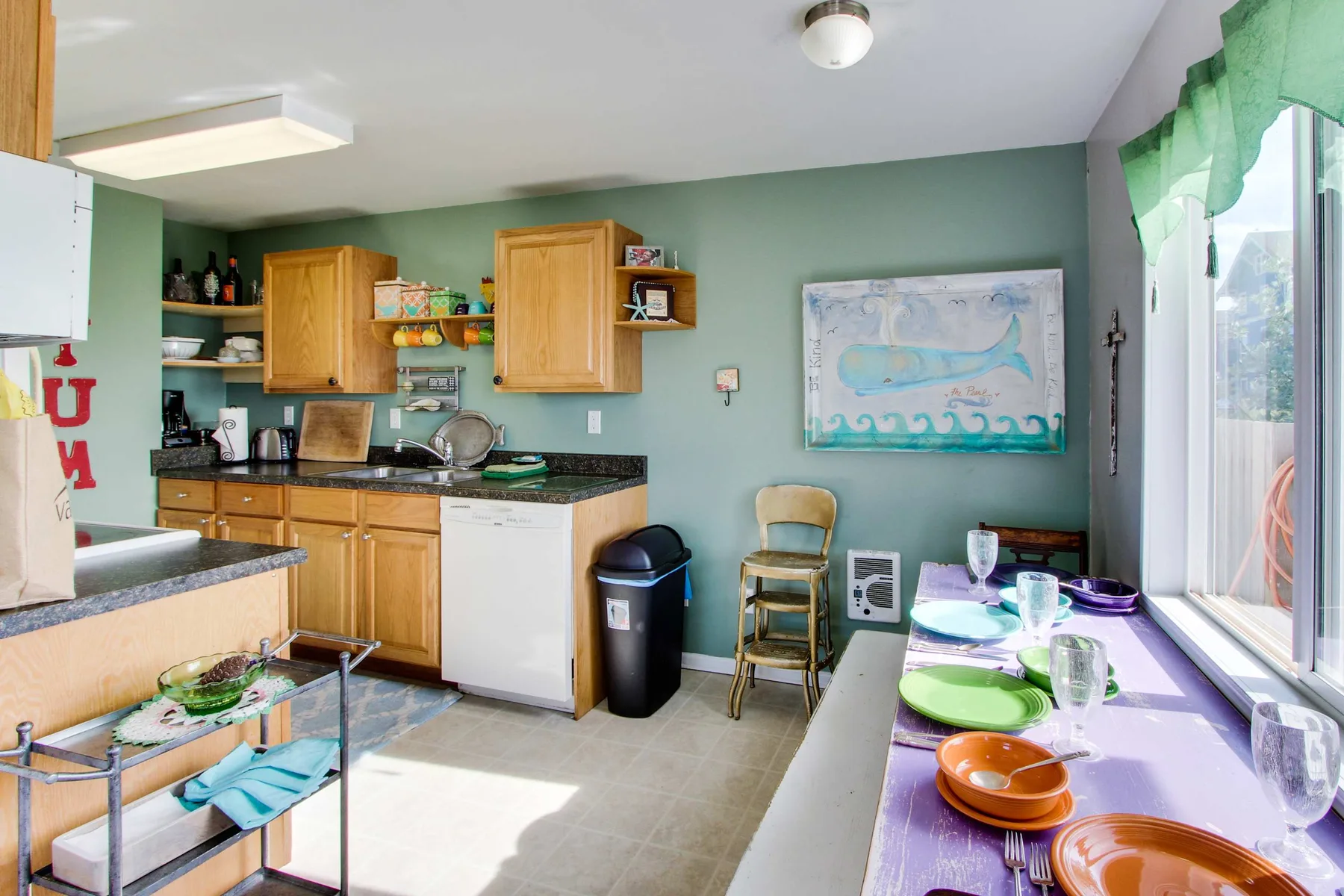 A kitchen dining area with wooden cabinets and a table set beside a large window.