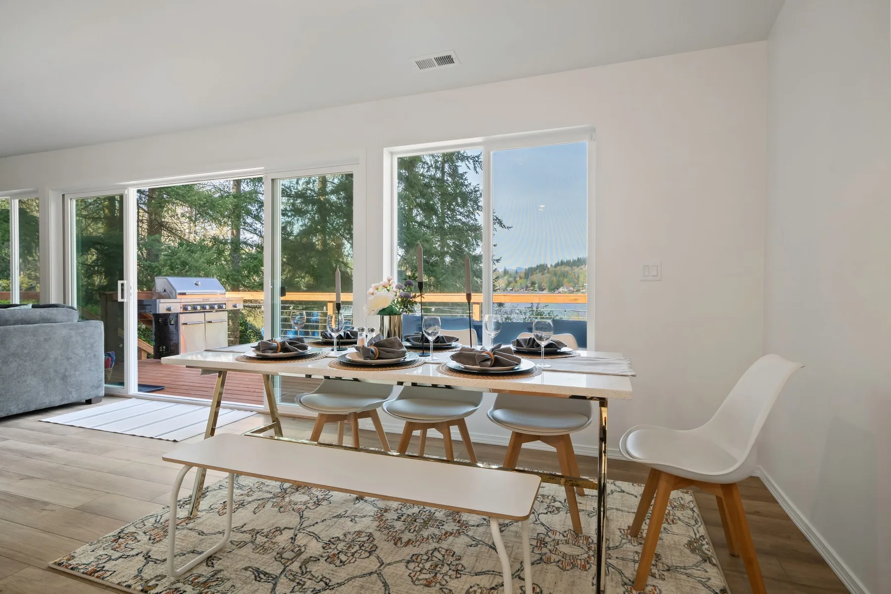 Un comedor luminoso con una mesa y grandes ventanas con vistas a los árboles.